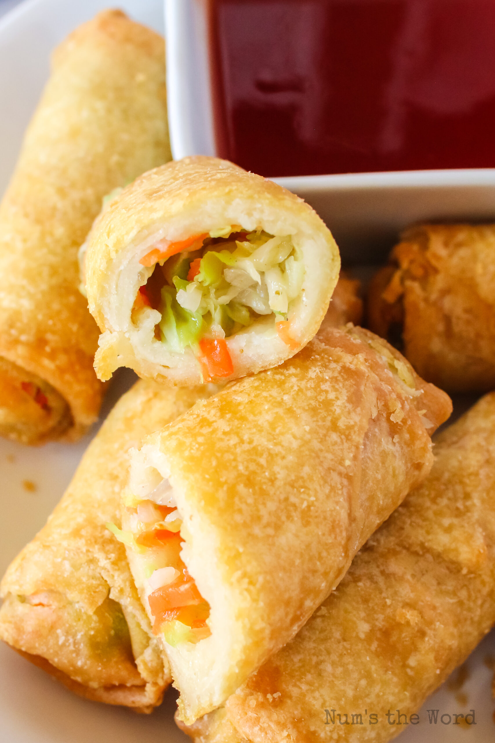zoomed in image of egg rolls on plate with one cut in half.