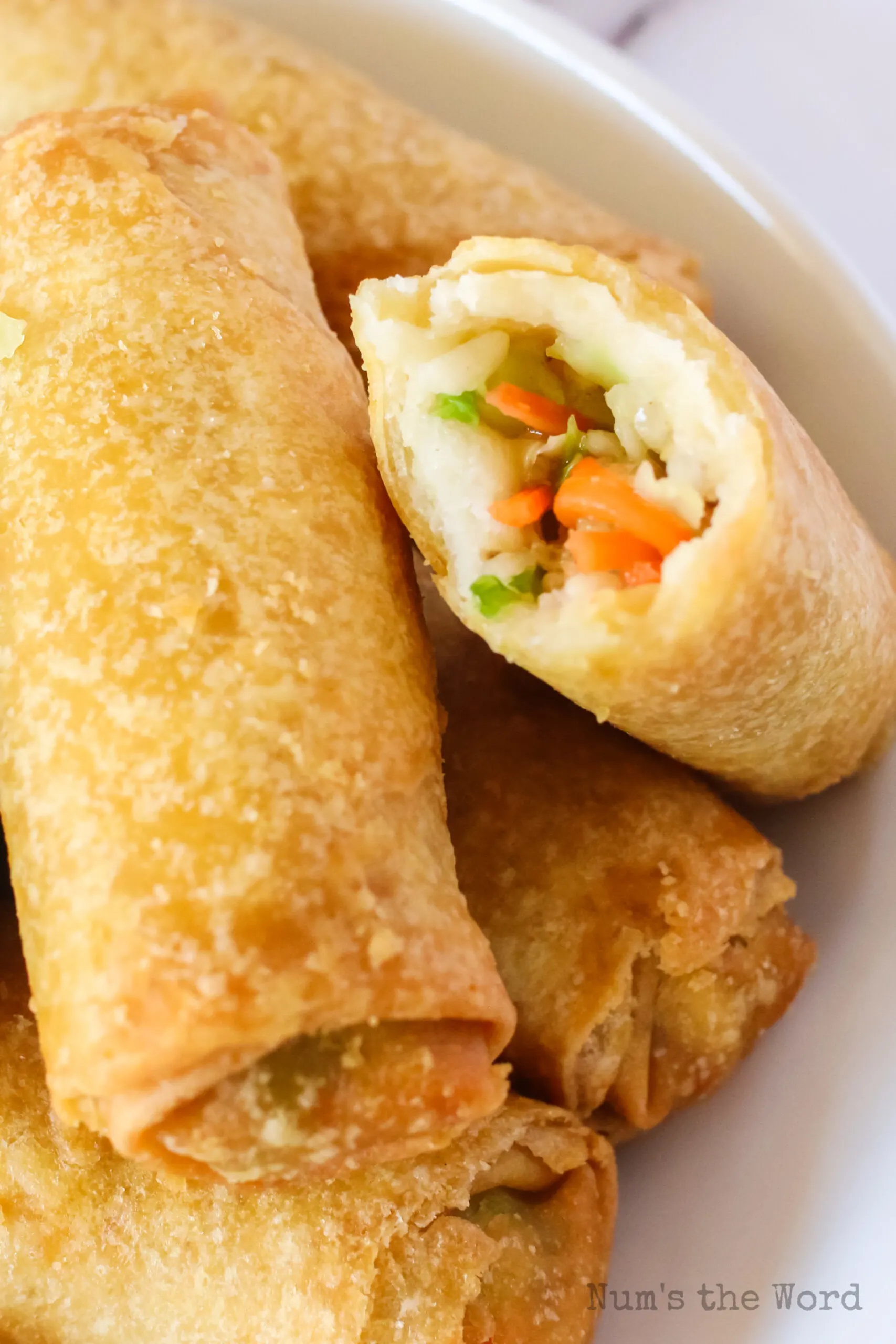 zoomed in image of egg rolls with one cut in half to show filing.