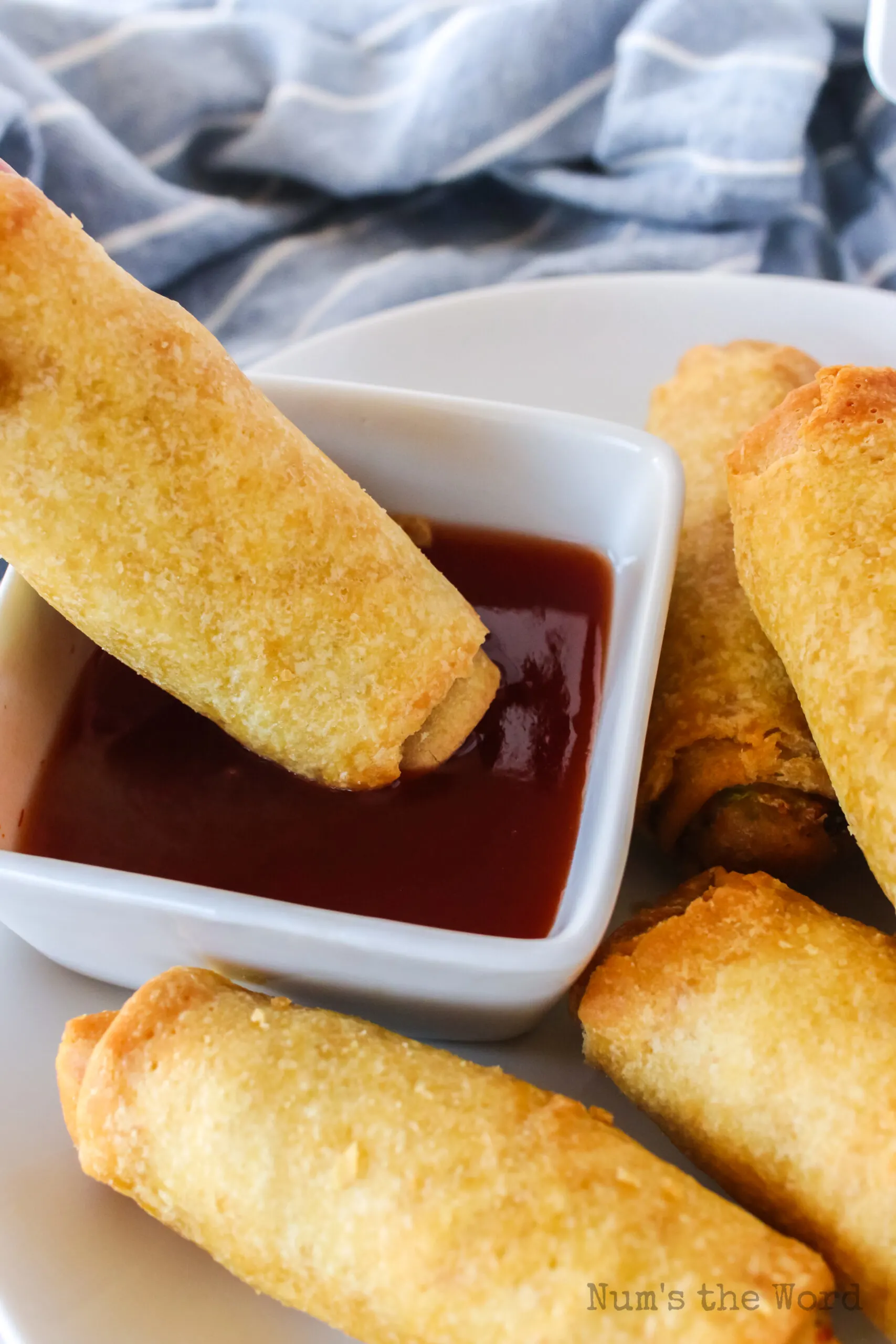 egg roll being dipped into a bowl of sweet and sour dipping sauce.