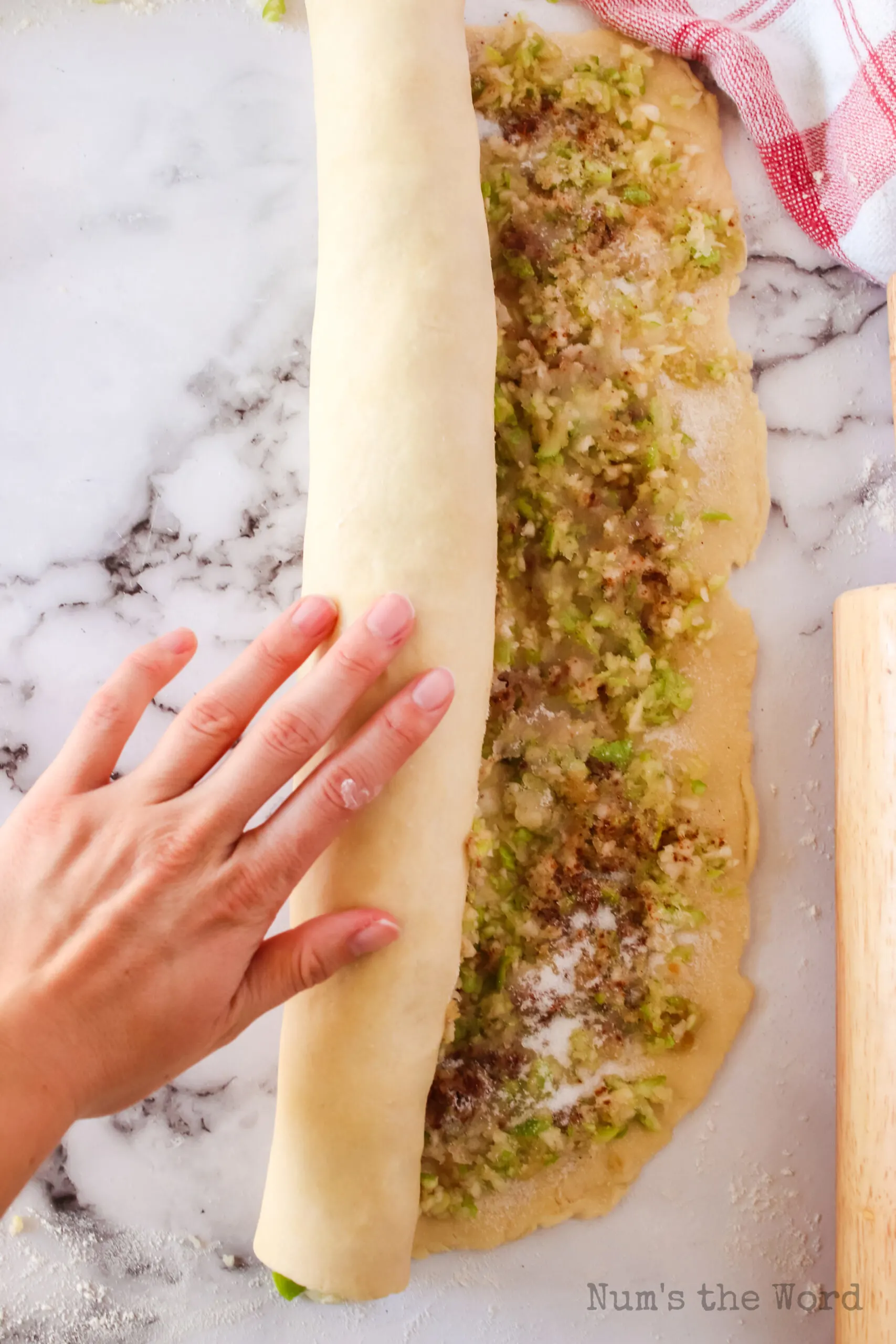 dough being rolled up into a cinnamon roll style