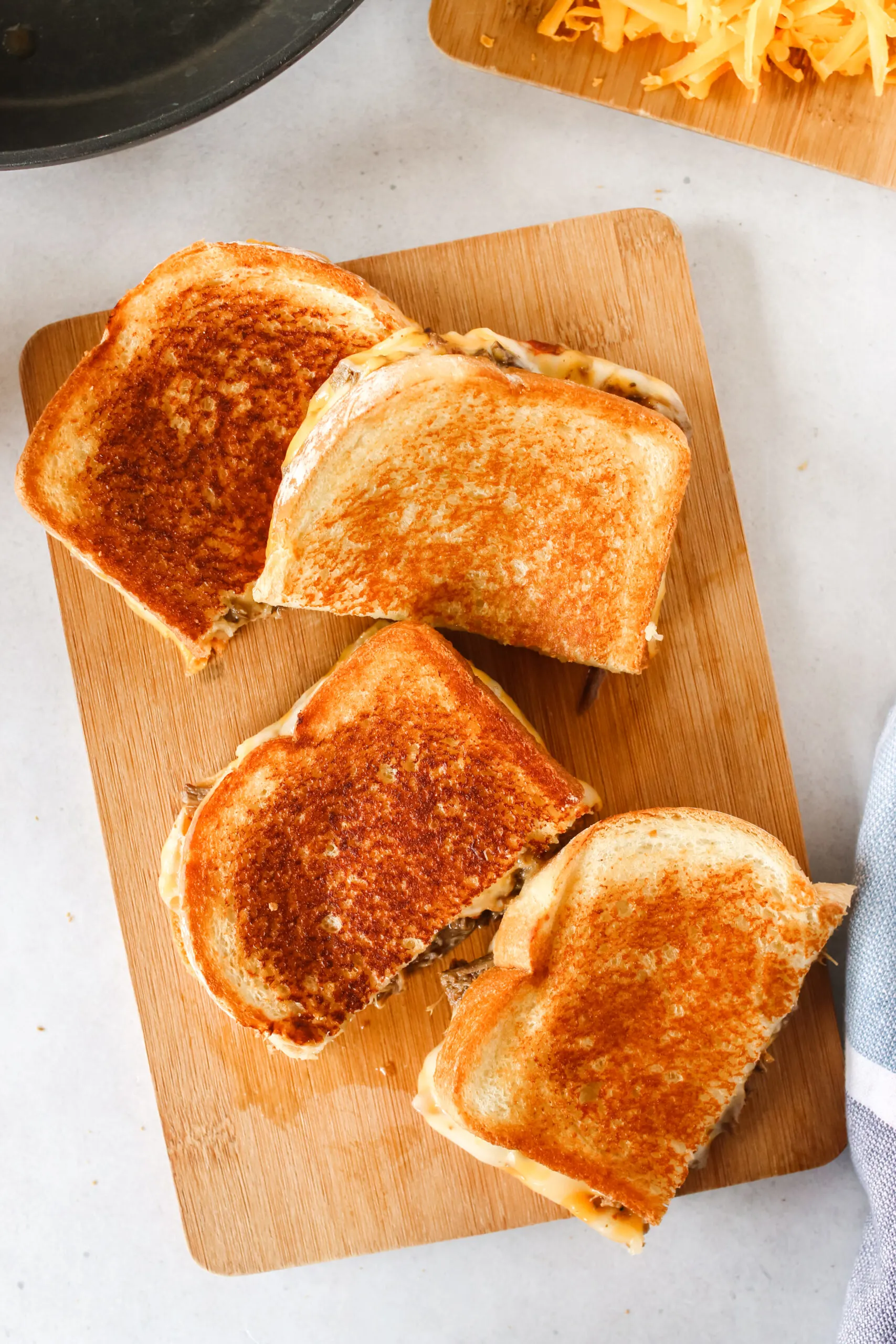 two grilled cheese sandwiches cut in half on a cutting board