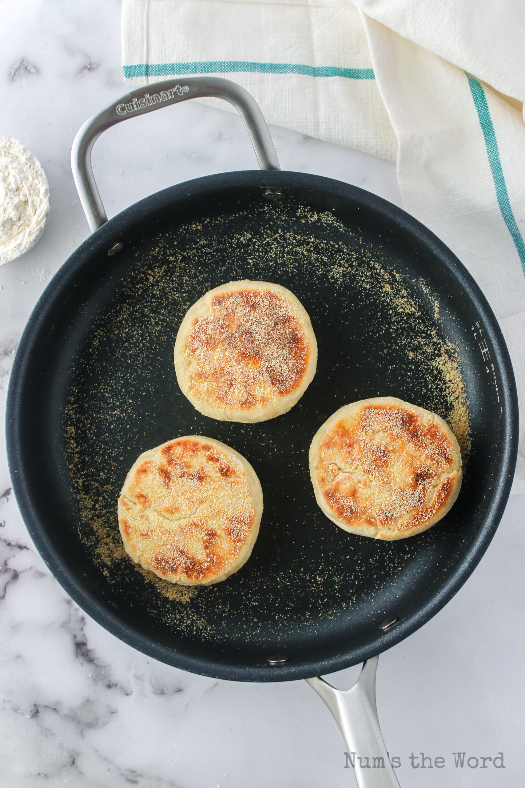 english muffins flipped over in skillet to show cooked side.