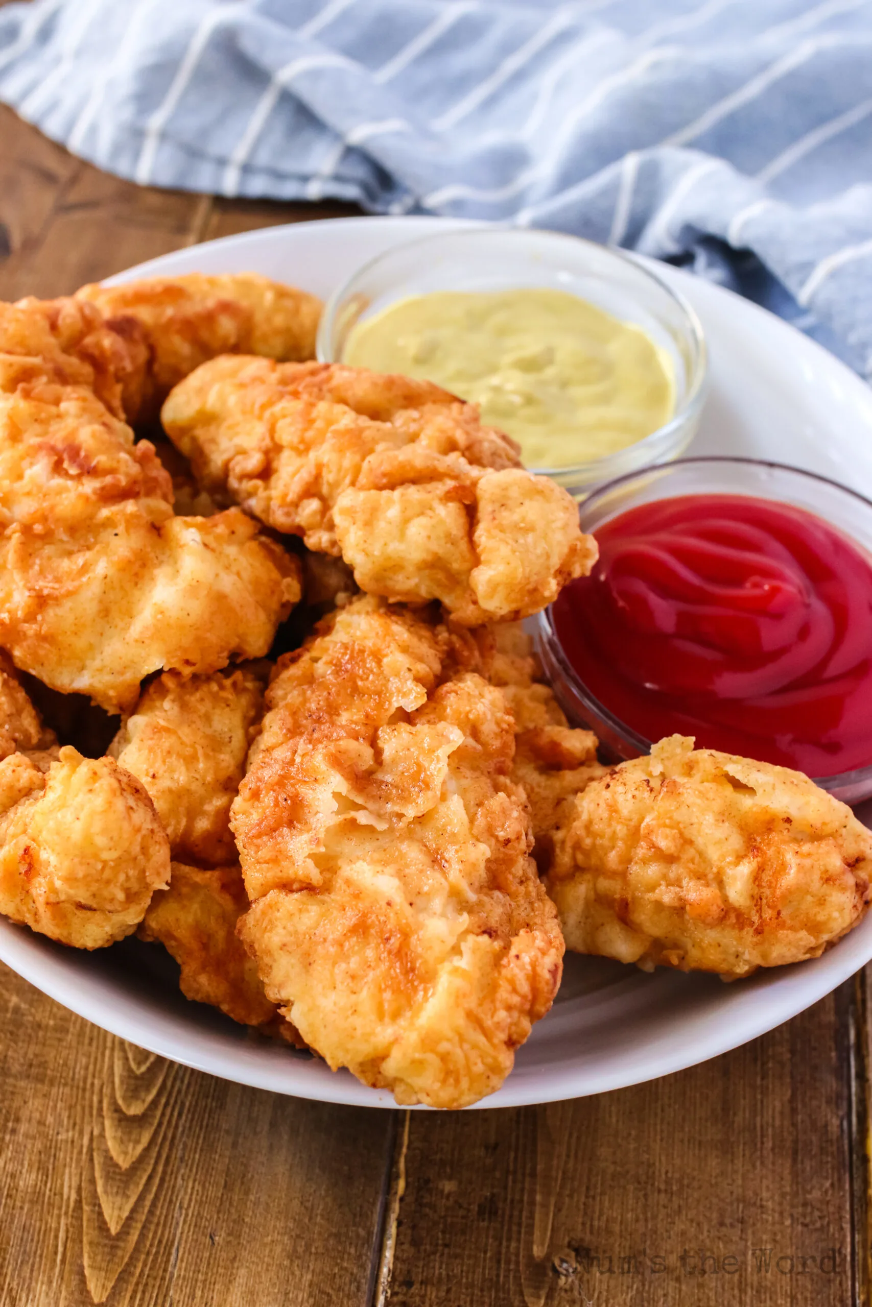 Fried chicken tenders on a plate with honey mustard and ketchup