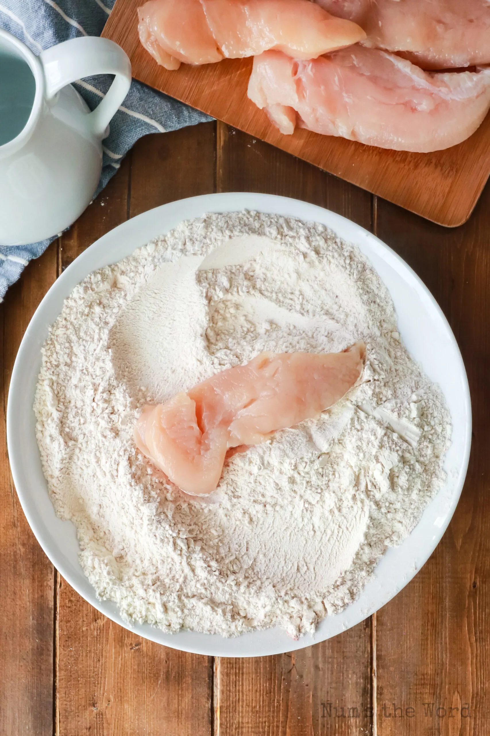 chicken tender laid on top of flour mixture, ready to coat.