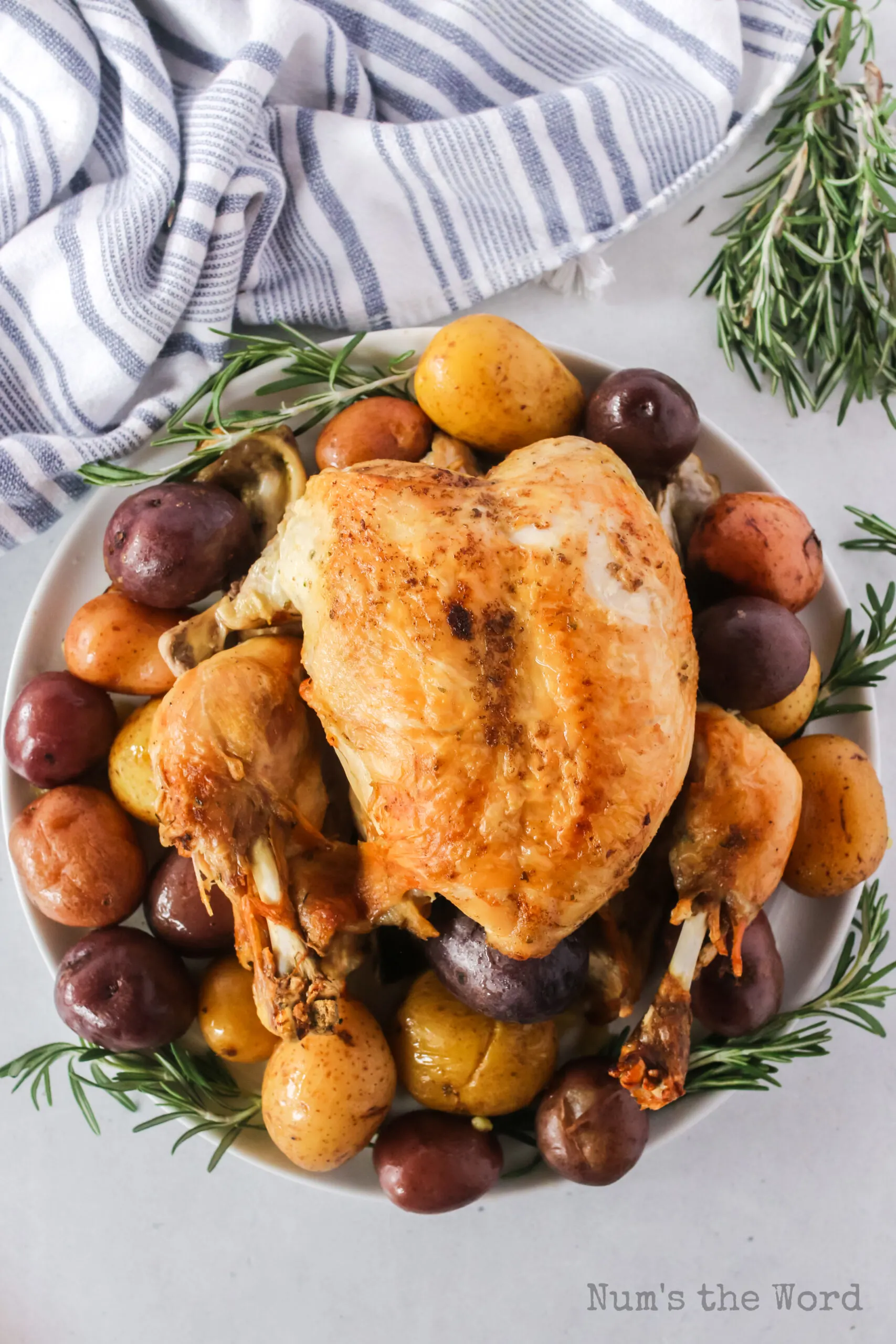 whole chicken roasted and on a platter with potatoes