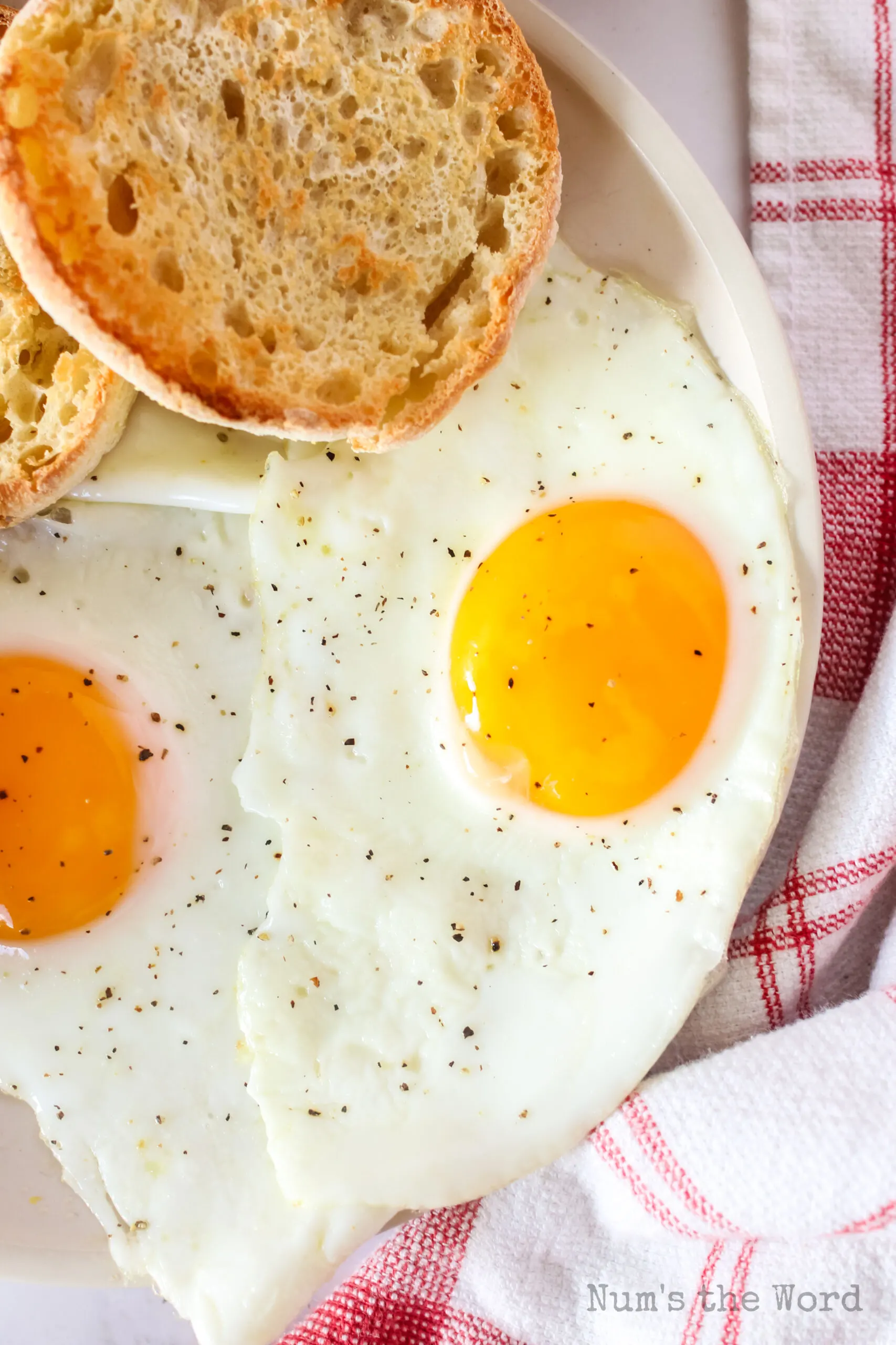 two eggs on a plate with english muffins