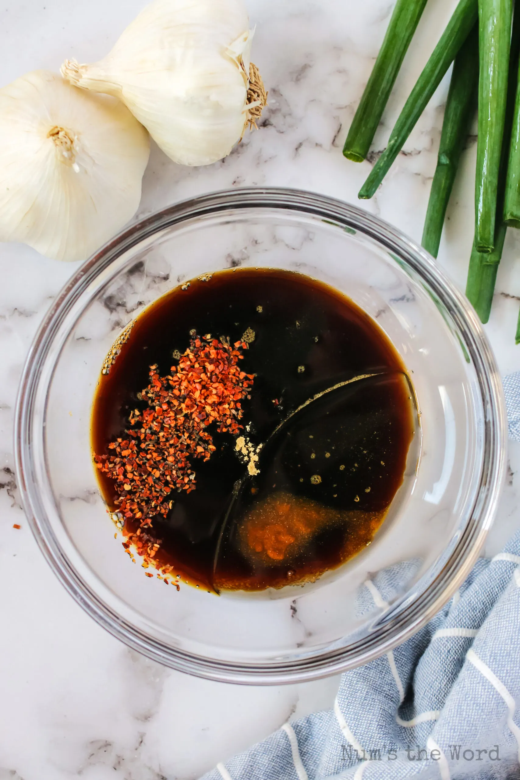 Brown sugar, woy sauce, sesame oil, ginger and red pepper flakes in a dish, unmixed.