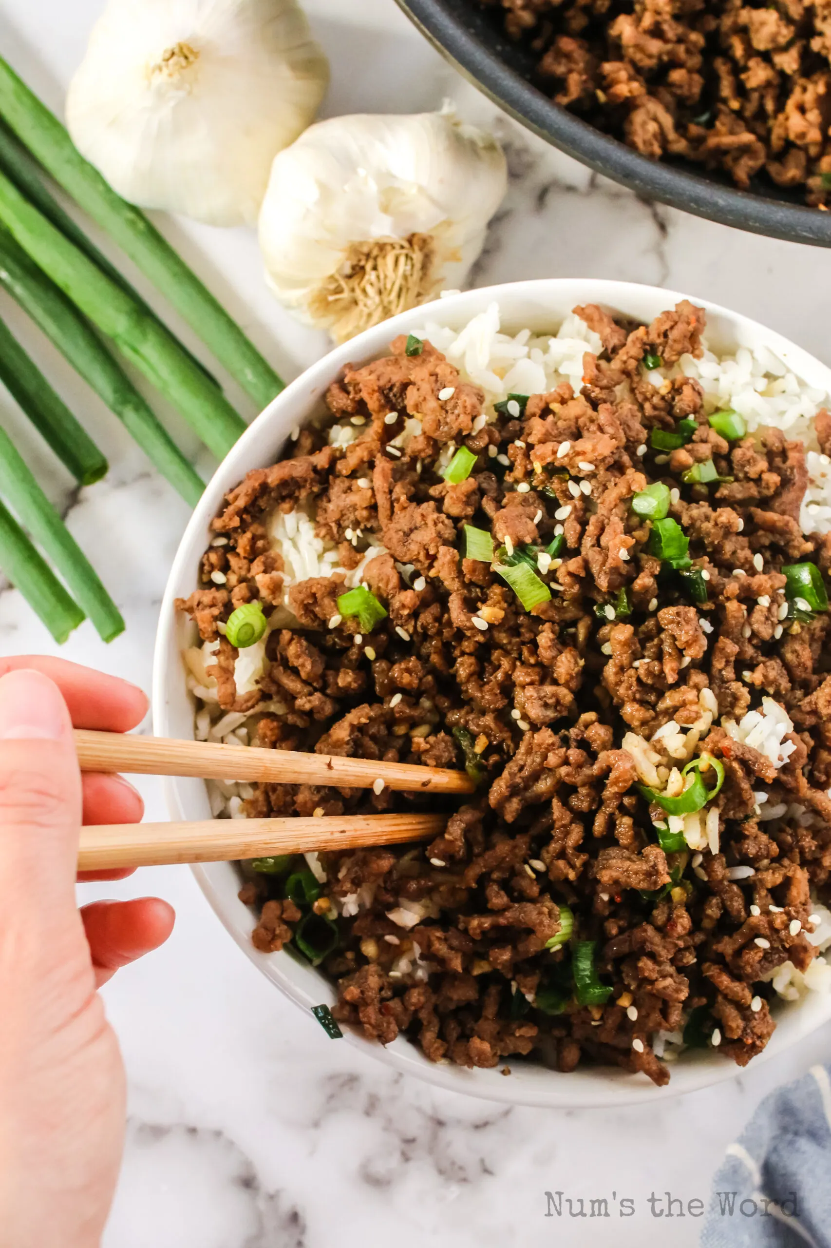 hand using chop sticks to eat beef