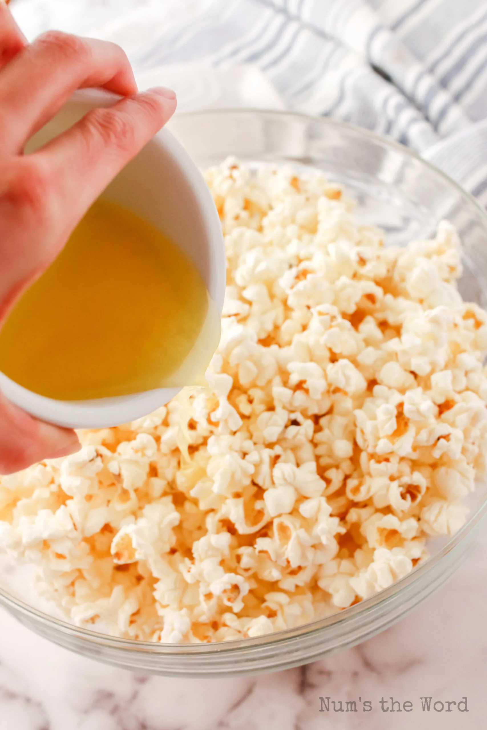 melted butter being poured over popped popcorn