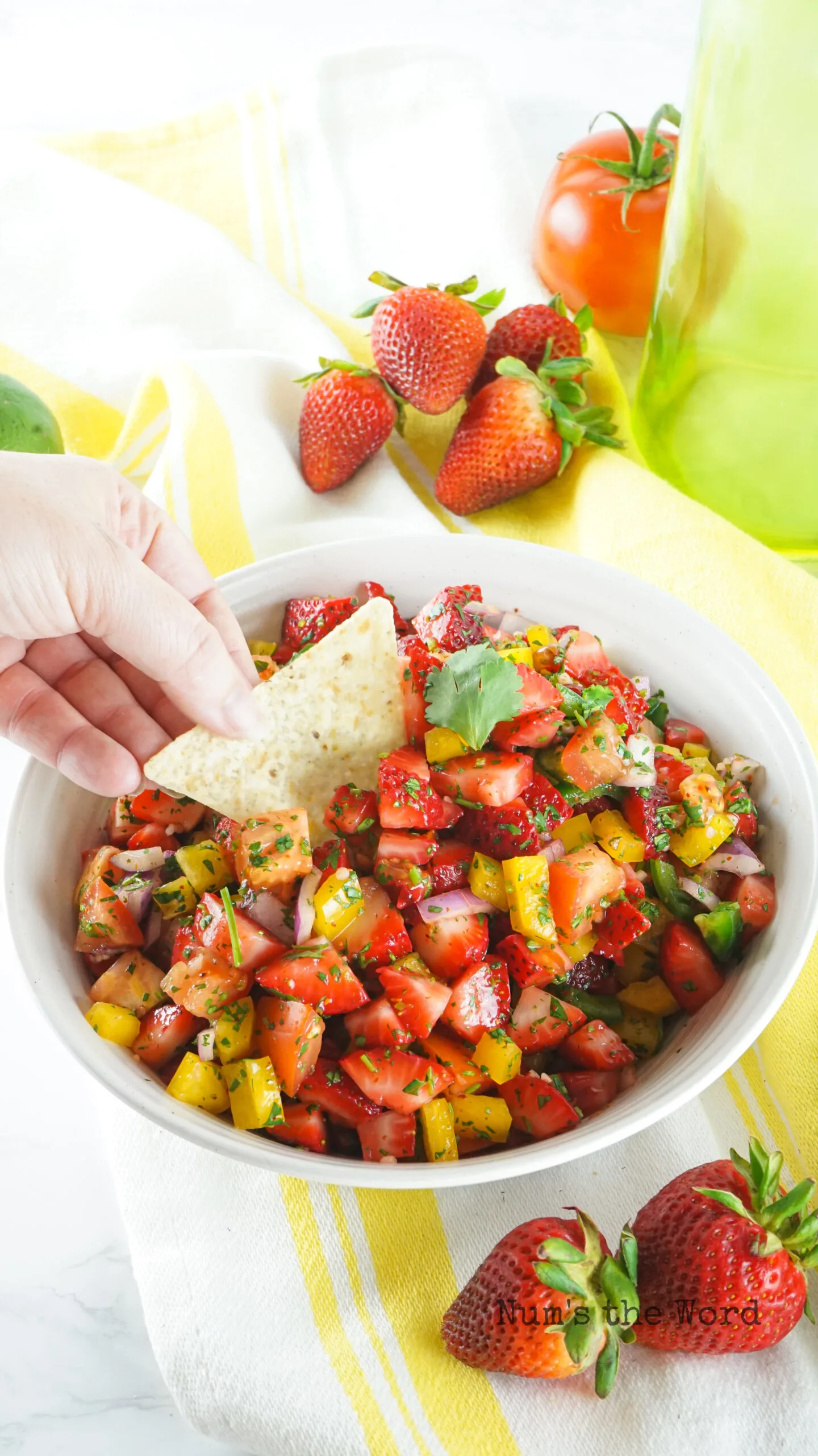 tortilla chip in bowl of salsa with hand scooping some out