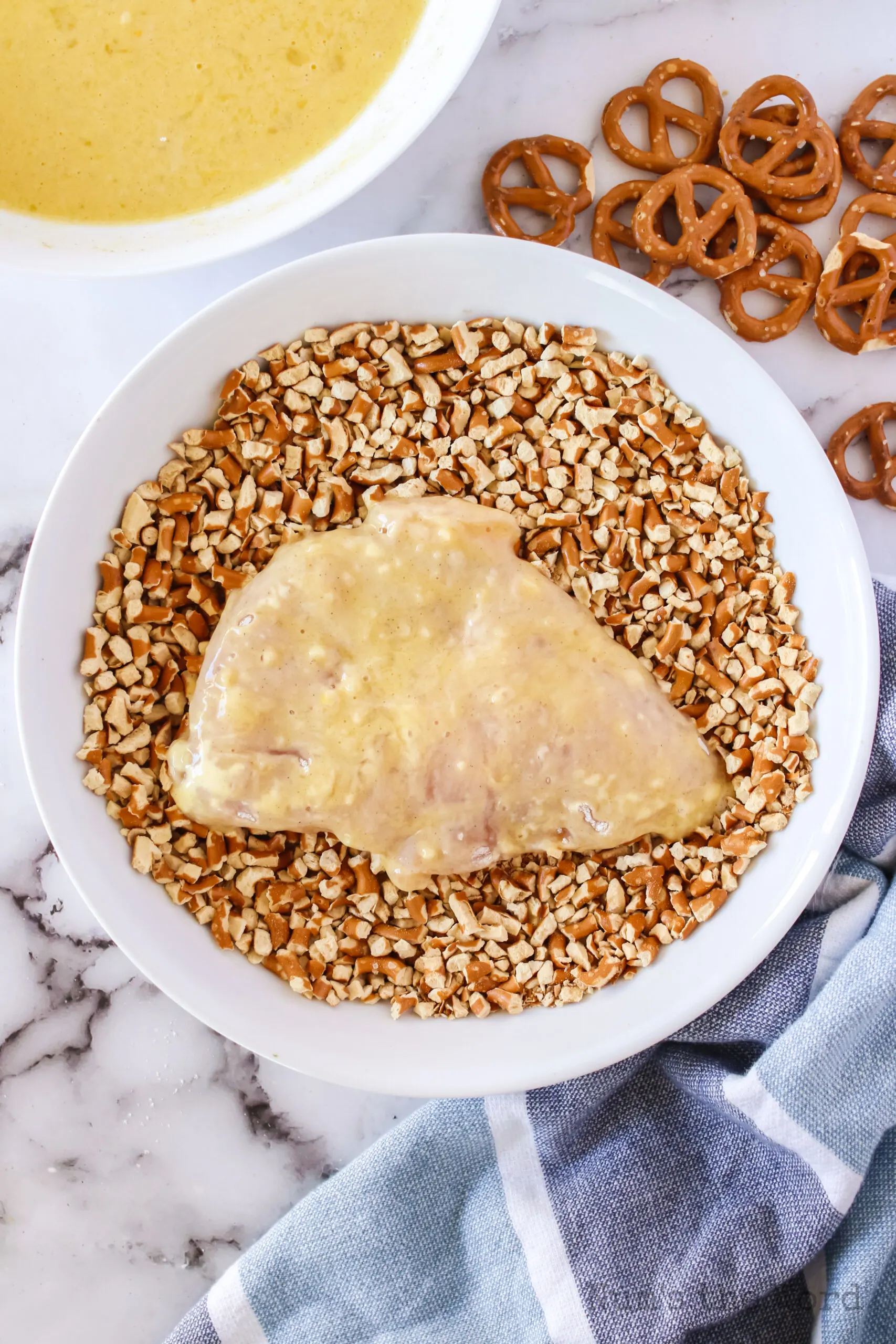 egg washed chicken in pretzel bowl, ready to be covered.