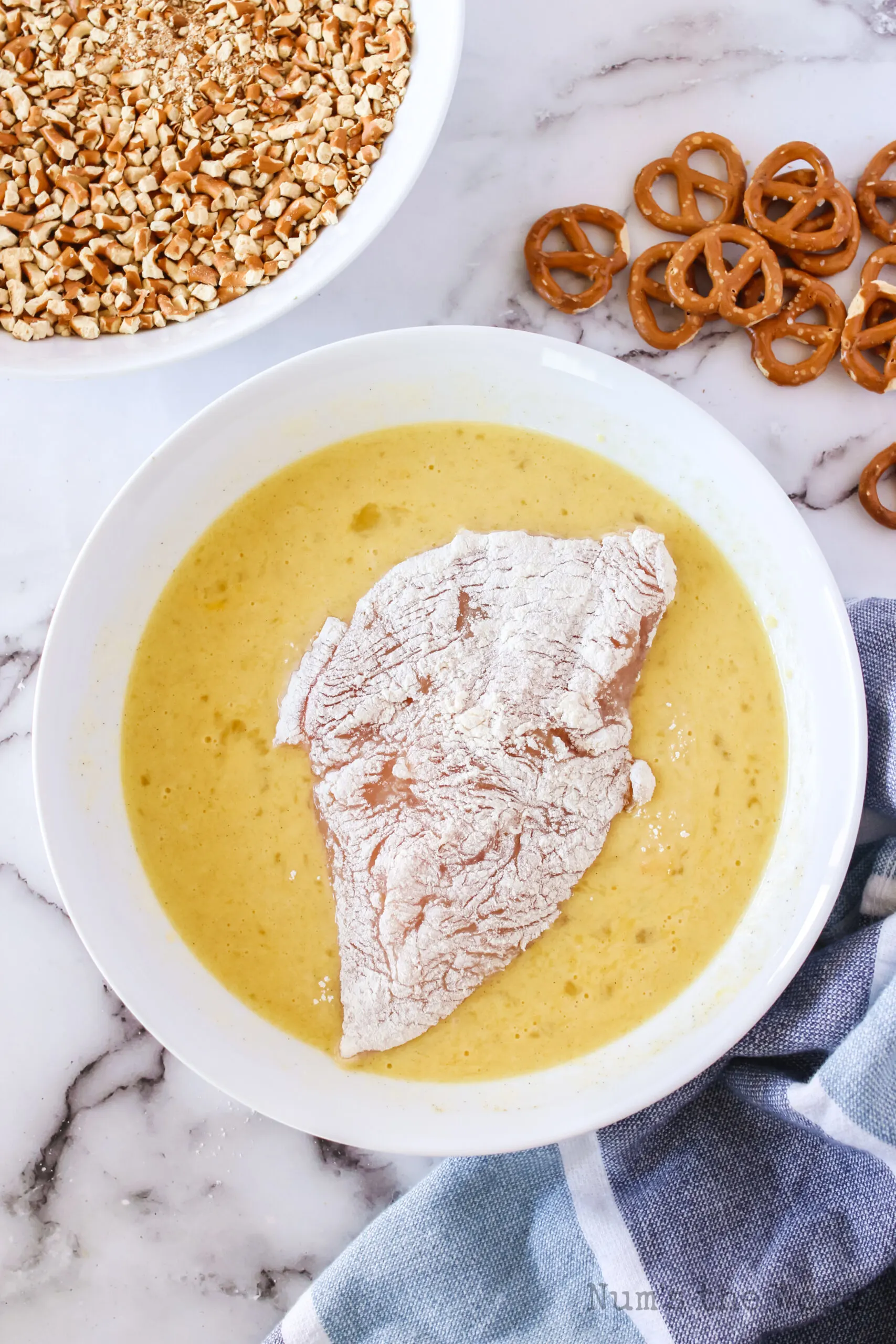 floured chicken in egg mixture - eggs, buttermilk, garlic and black pepper