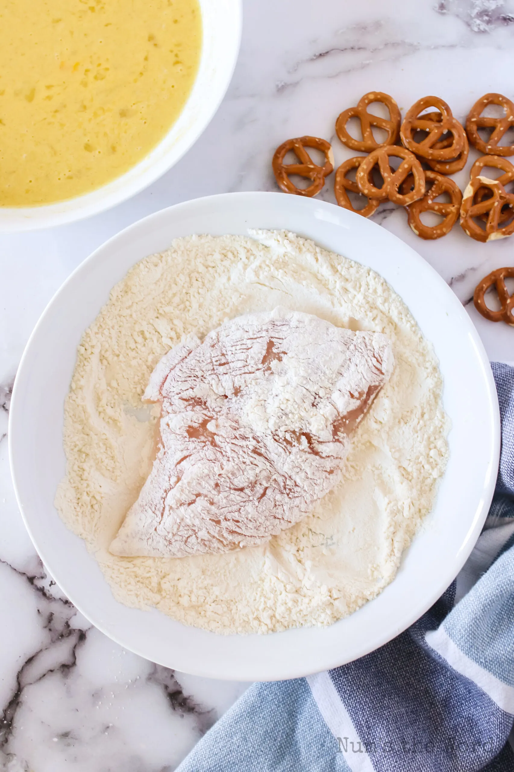 chicken breast covered in flour in flour bowl.