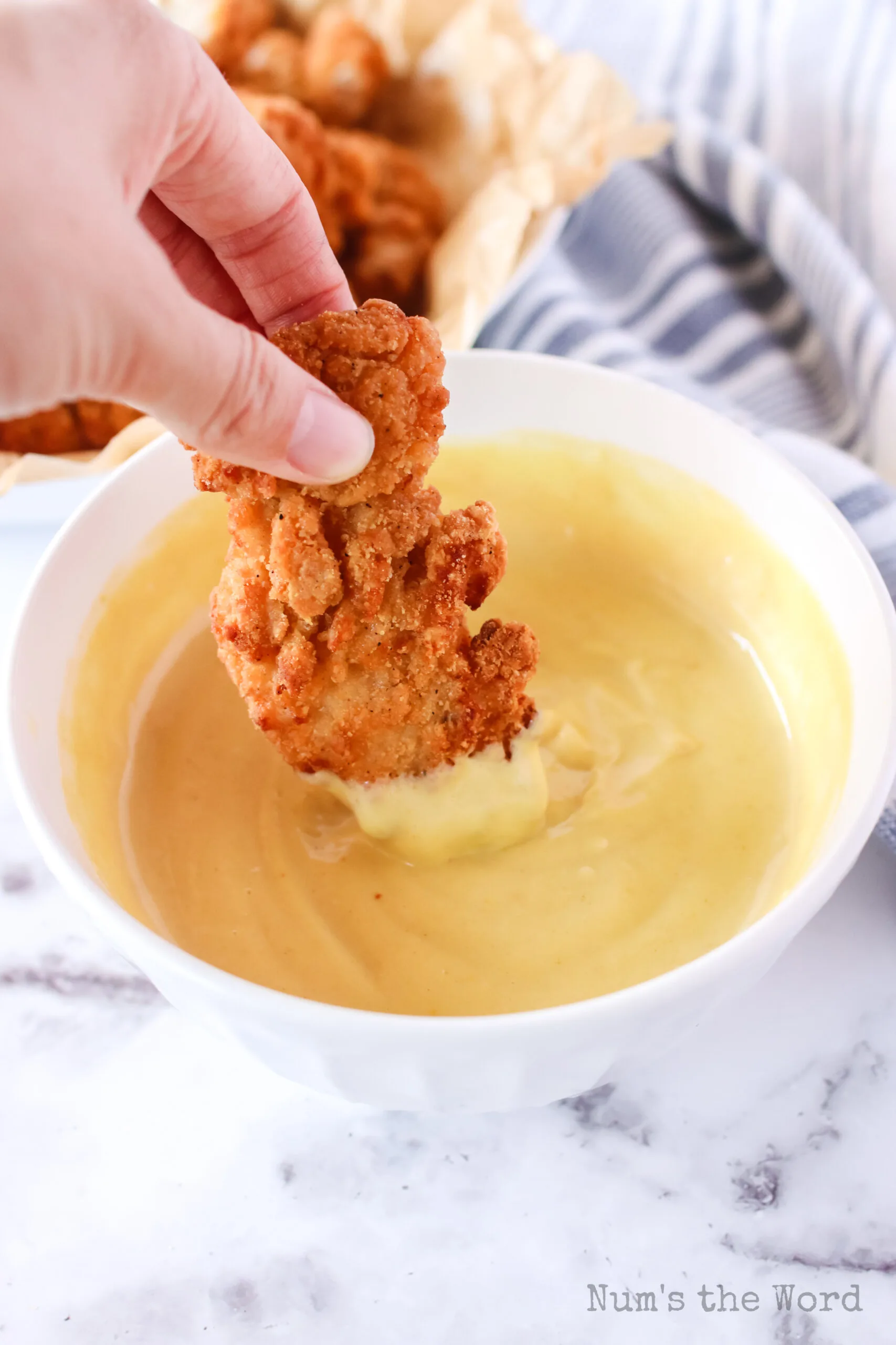 chicken strip being dipped into honey mustard