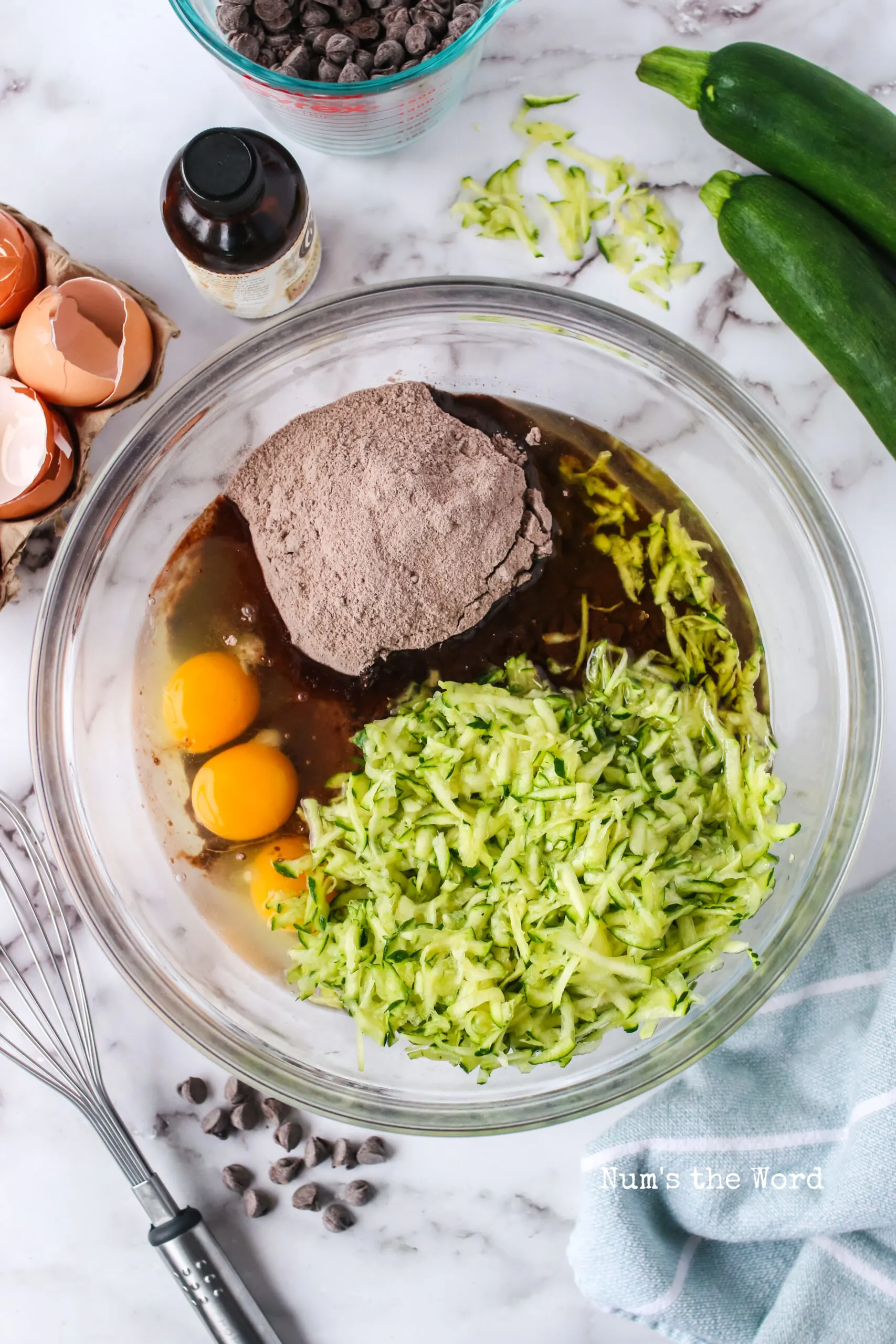 all ingredients for chocolate zucchini cake in a bowl, ready to mix