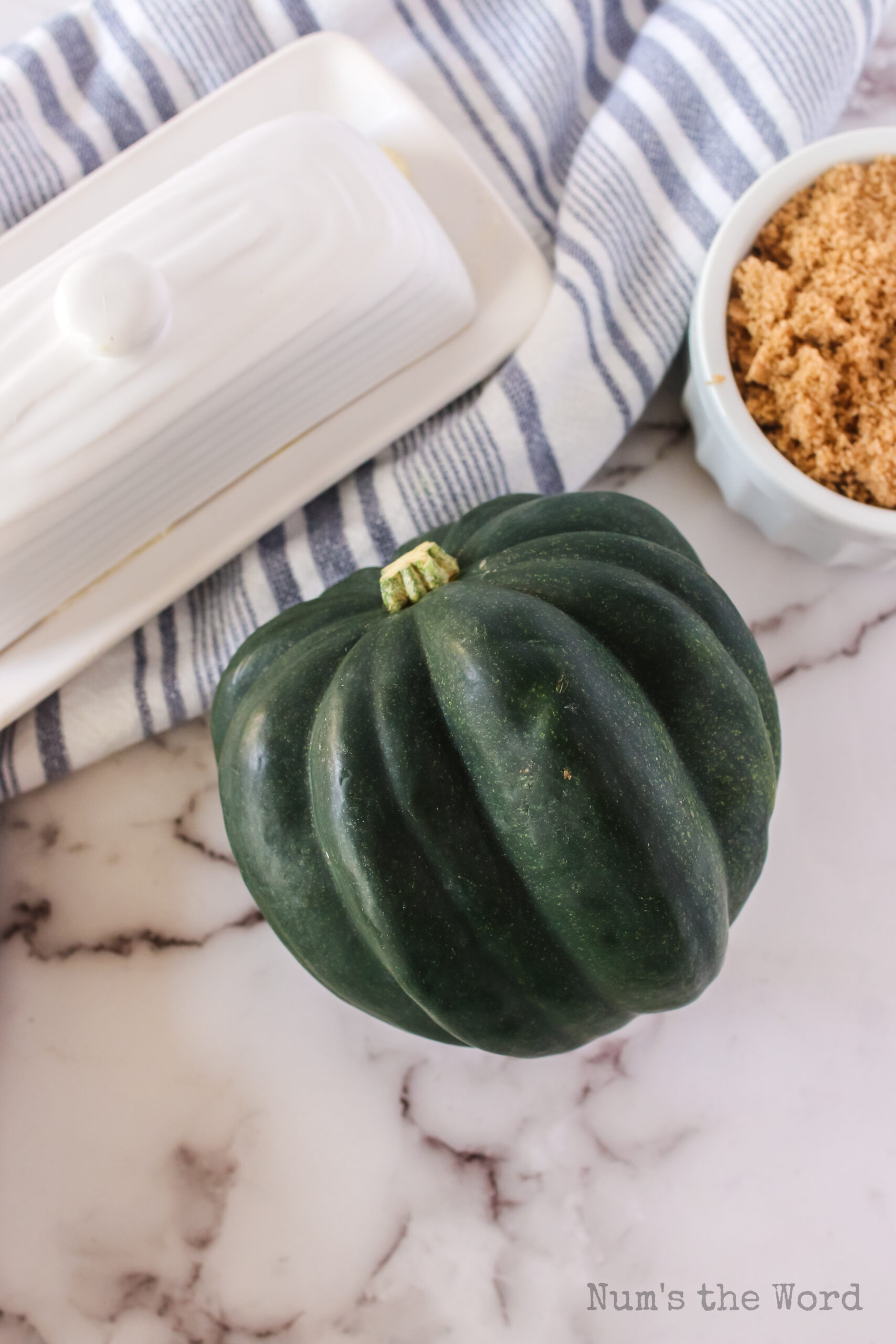 acorn squash next to a butter dish and bowl of brown sugar