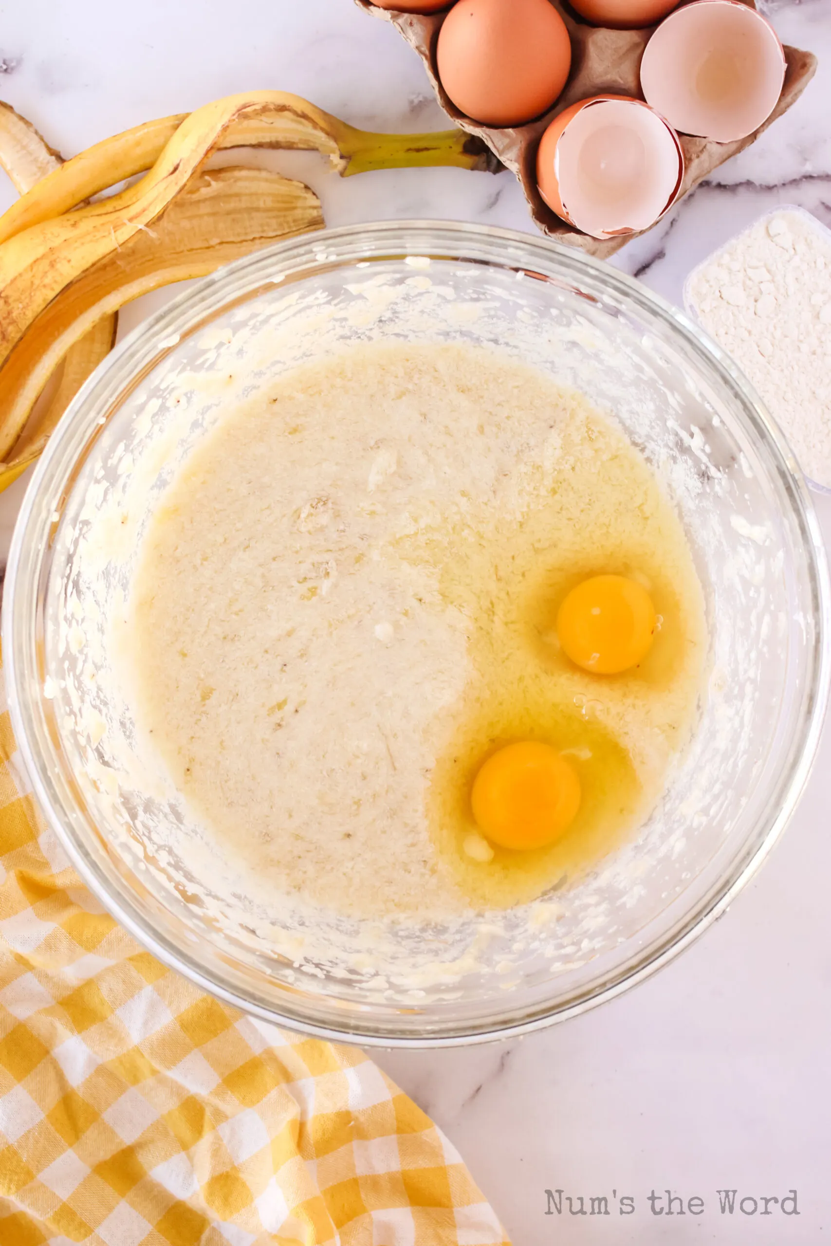 bananas sugar and butter blended together in a bowl with eggs added on top