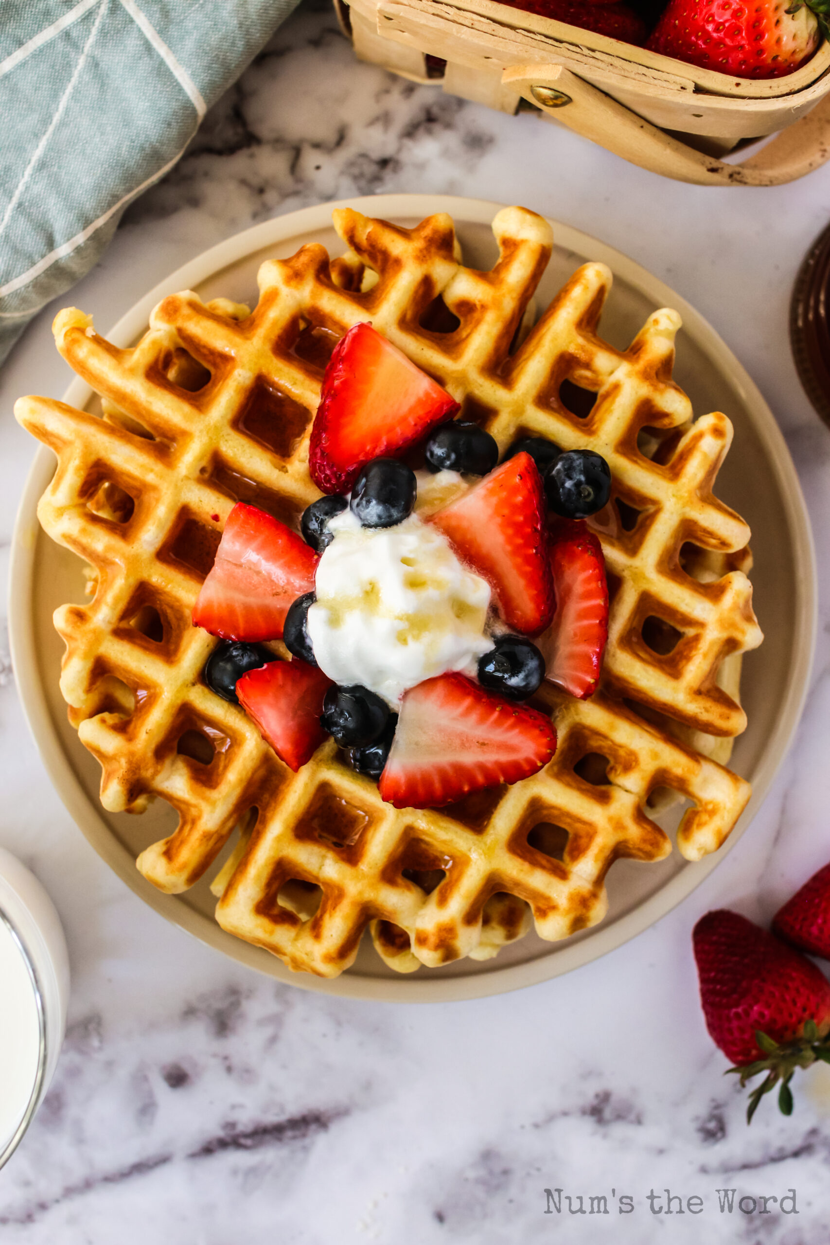 waffles on plate with fresh fruit and butter. Photo taken from the top looking down