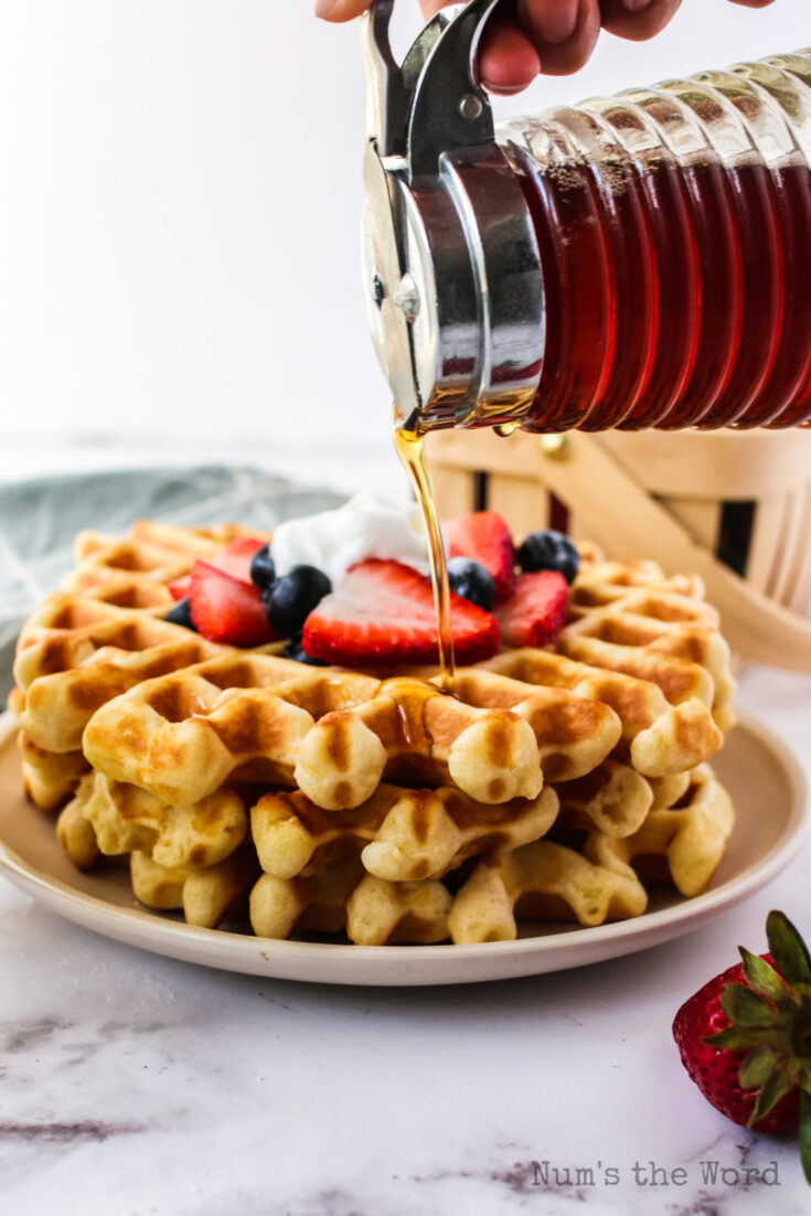 maple syrup being poured on top of waffles