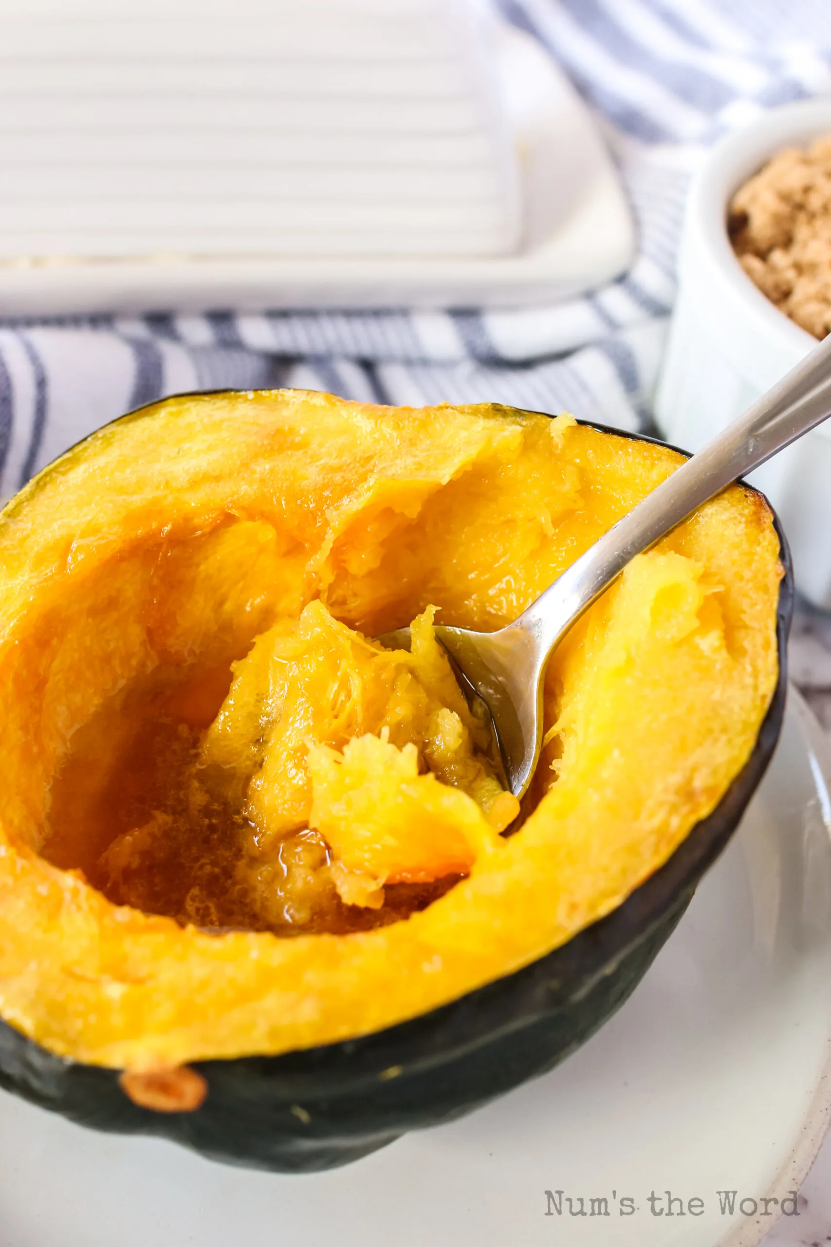 cooked squash half on a plate with a fork full being scooped out of the middle.