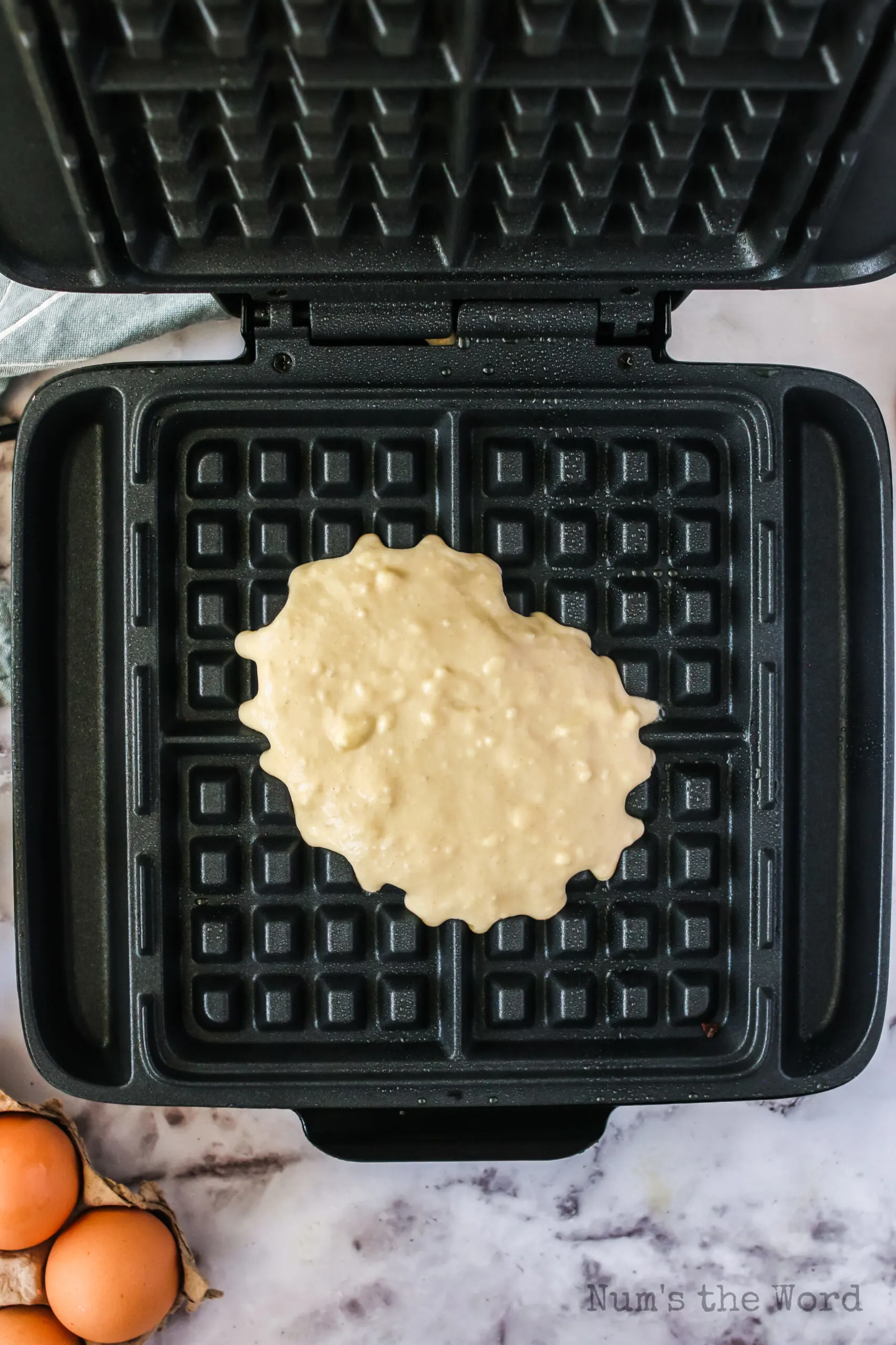 belgian waffle dough poured into a waffle iron