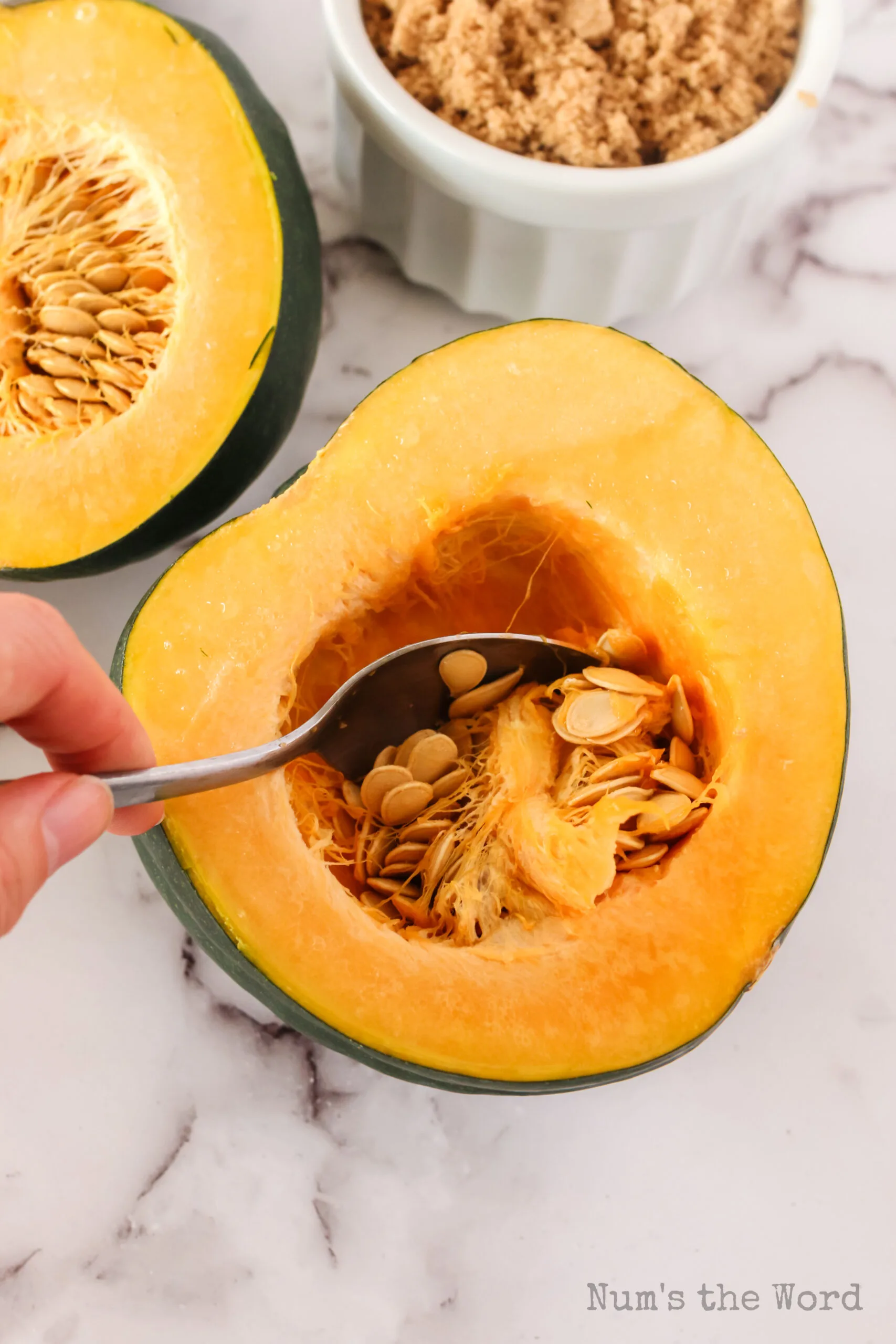 spoon scraping out acorn squash seeds