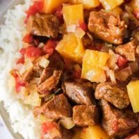 close up of beef and pineapple over rice on a plate