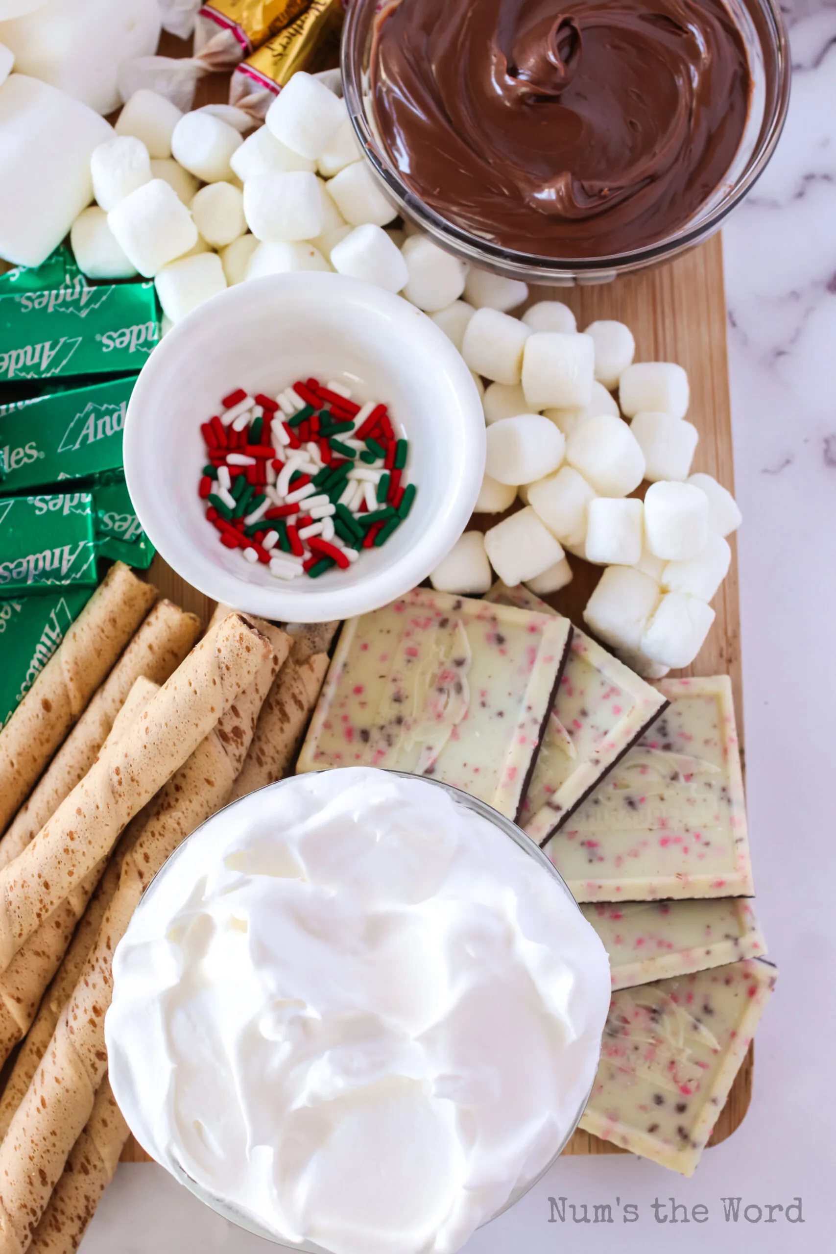 marshmallow fluff, mints, sprinkles, marshmallows, peppermint bark and cookies on board