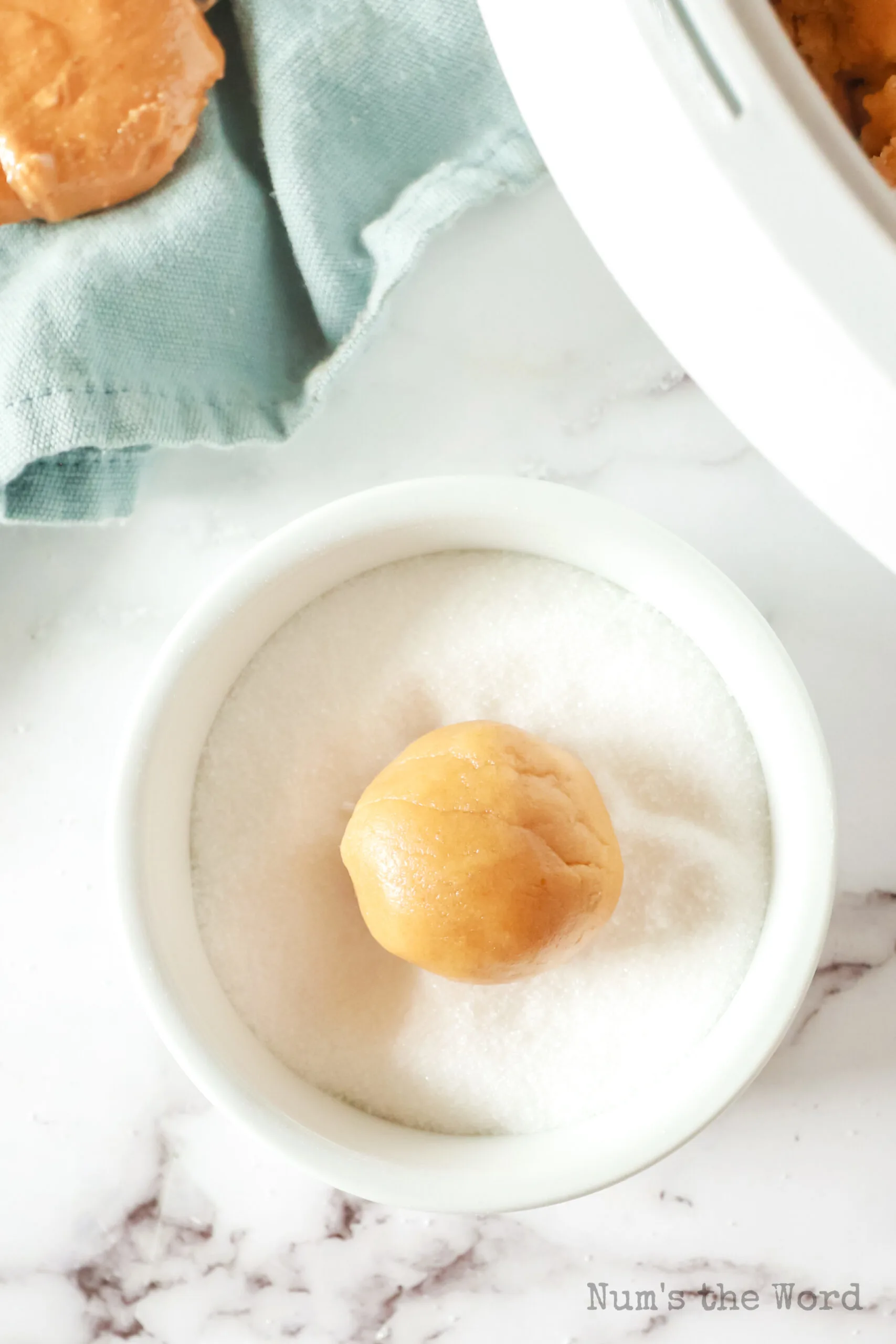 peanut butter dough ball in a bowl of sugar