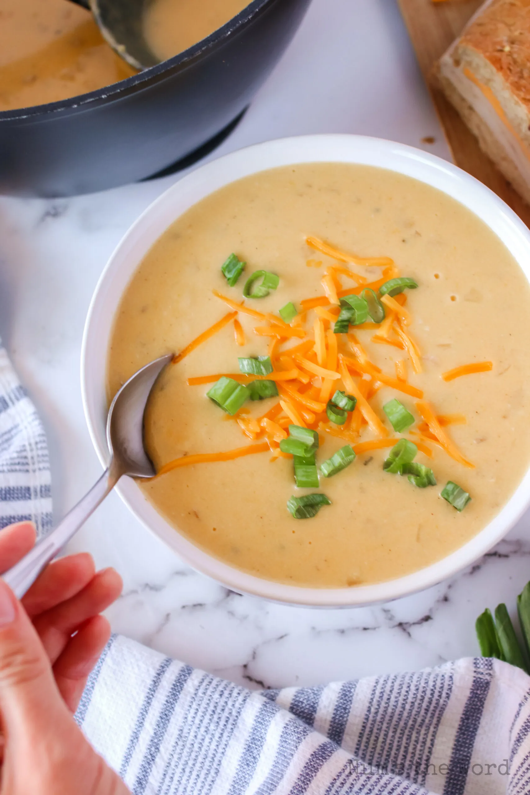 zoomed out image of soup in bowl with garnishes and spoon