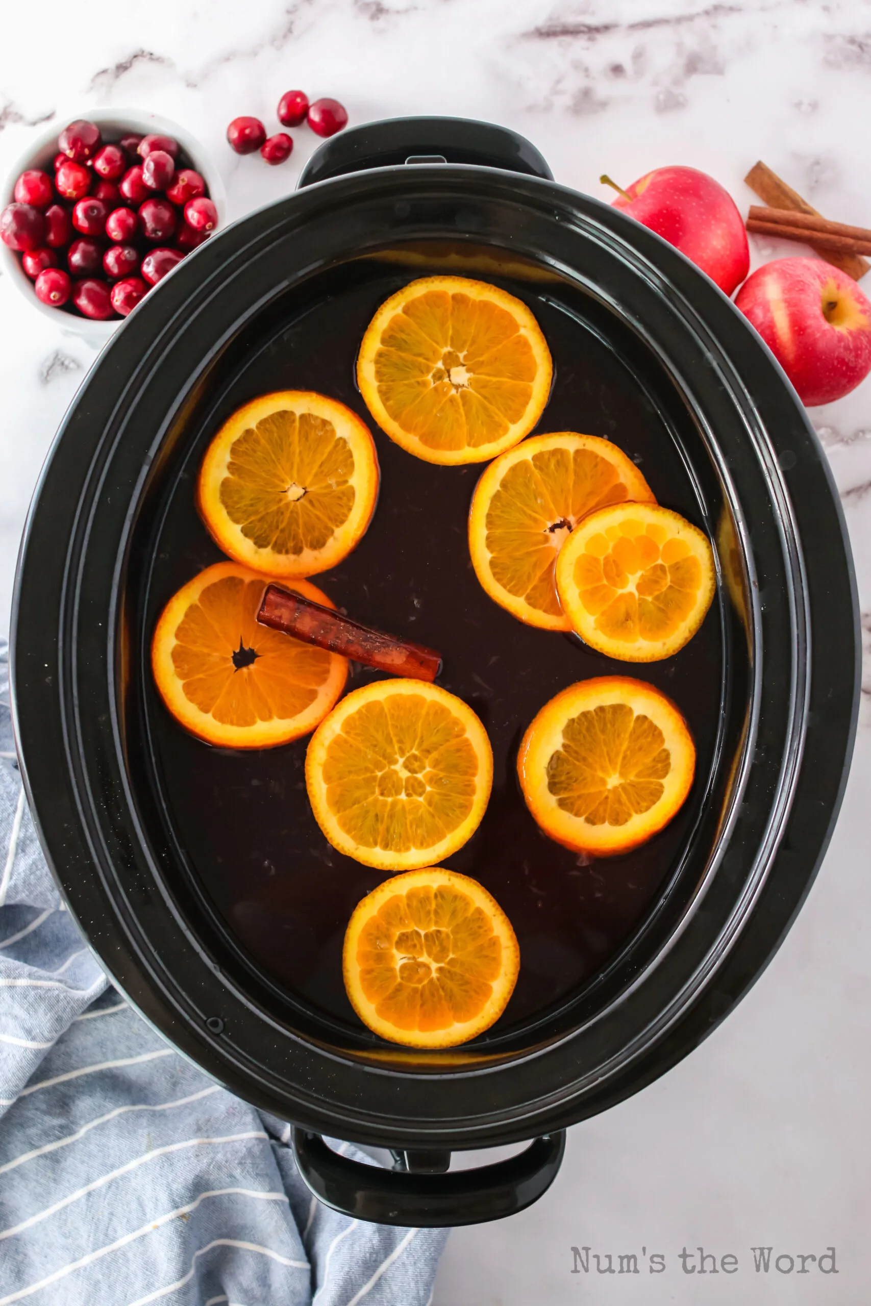 top view of slow cooker with orange slices and cider