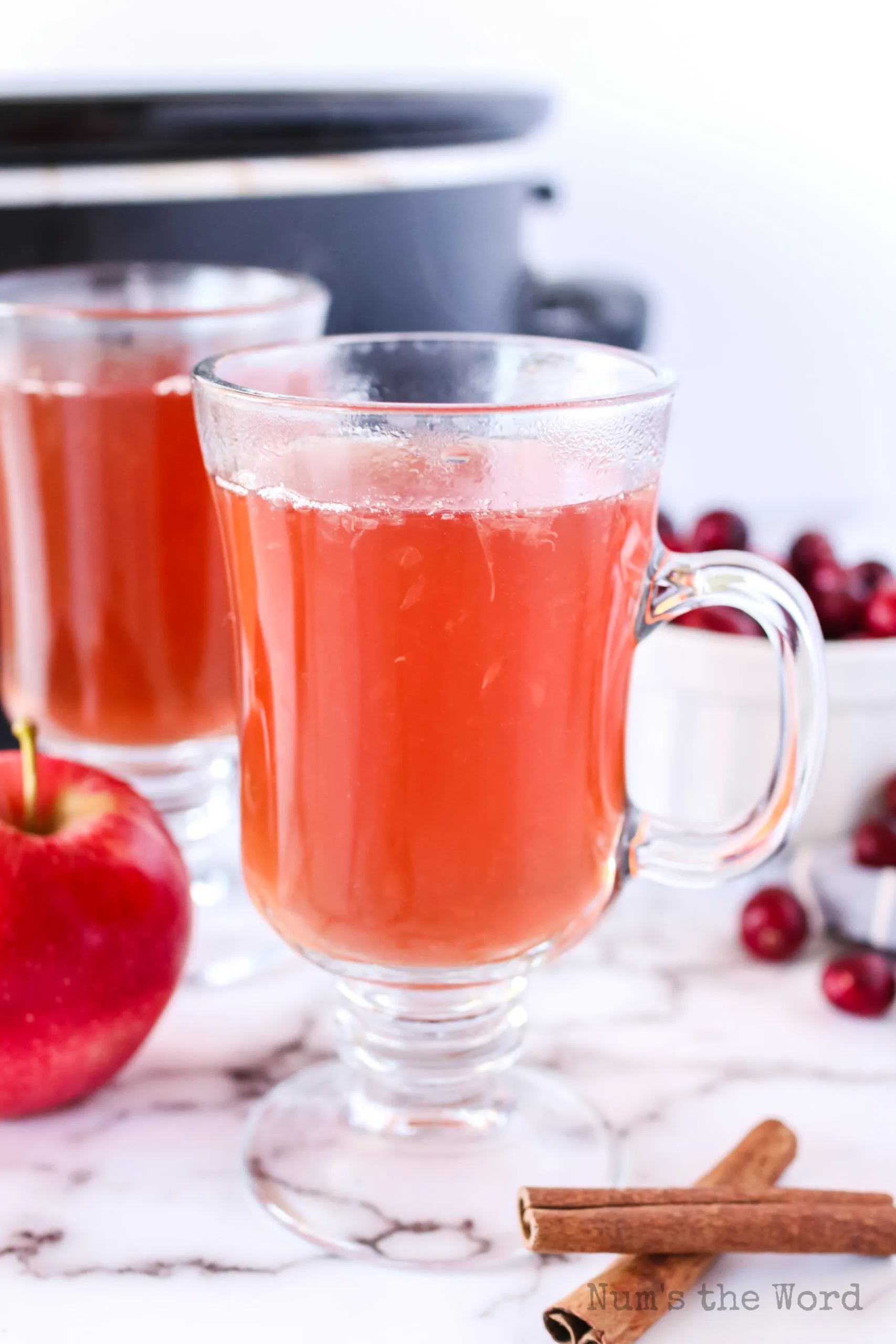 two glasses of cider with crock pot in background