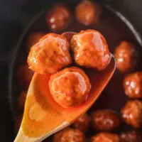 spoon holding up 3 meatballs on wooden spoon