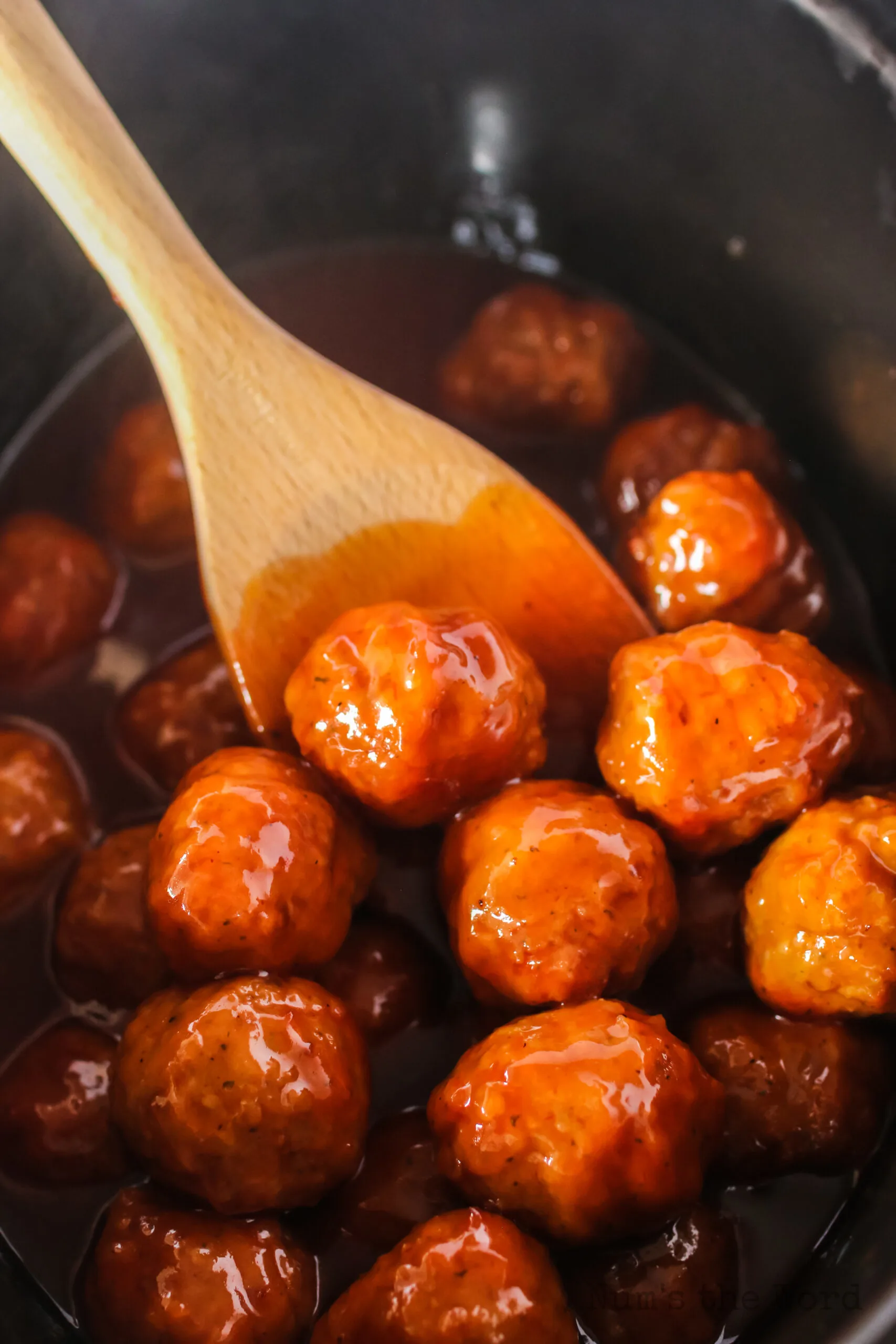 spoon holding up a meatball in crock pot