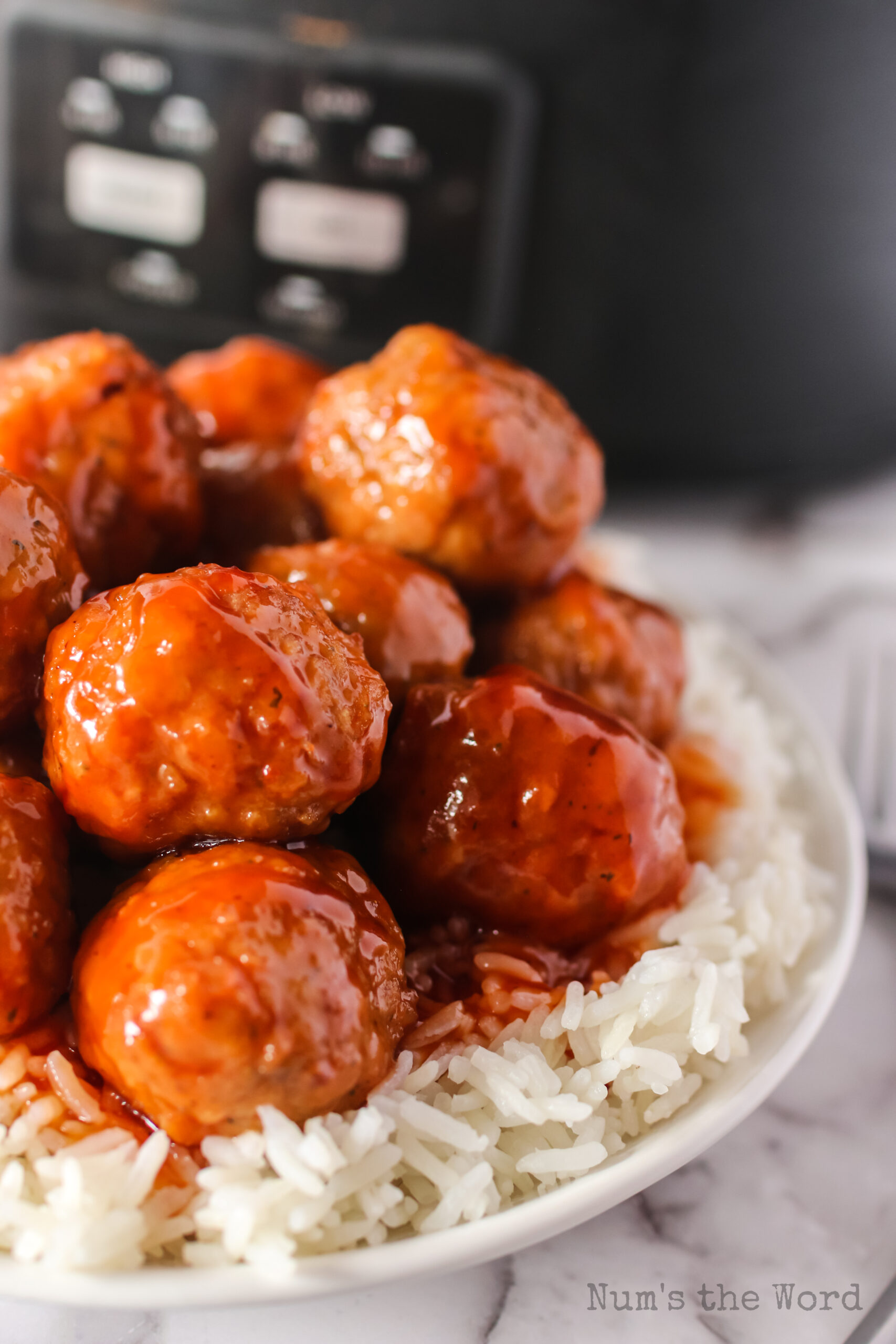 zoomed in side view of meatballs stacked up on plate with rice