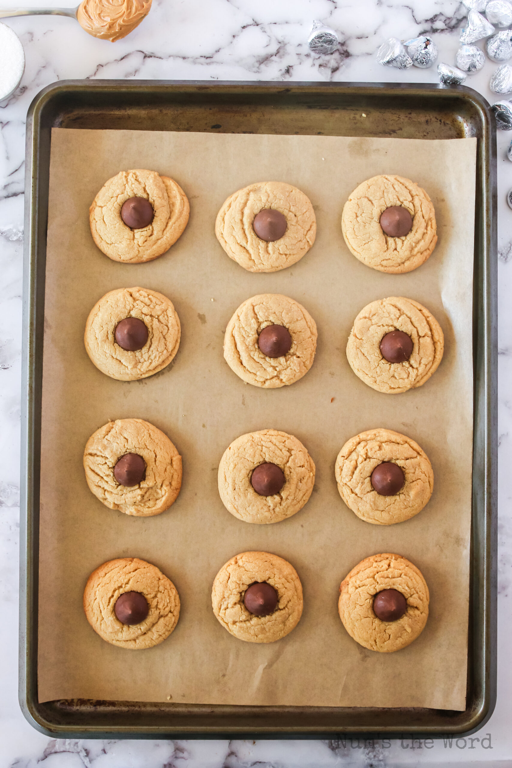 fresh baked cookies on pan with a kiss pressed into the center of each cookie