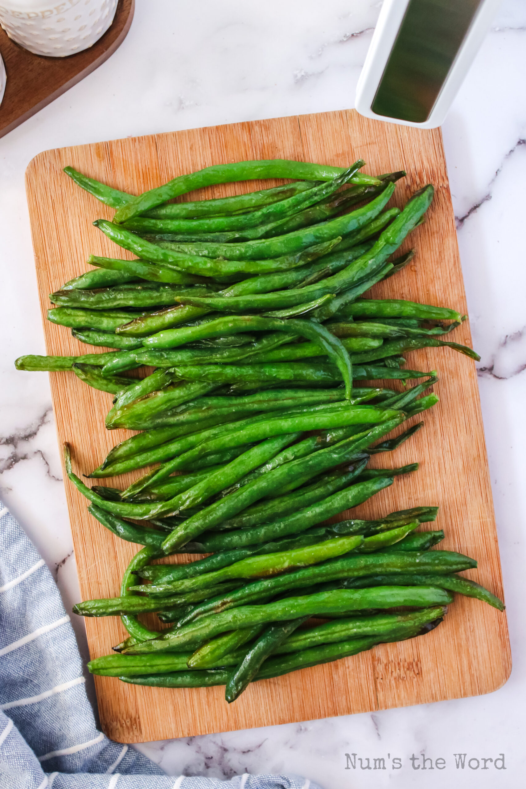 cooked green beans on serving board at an angle