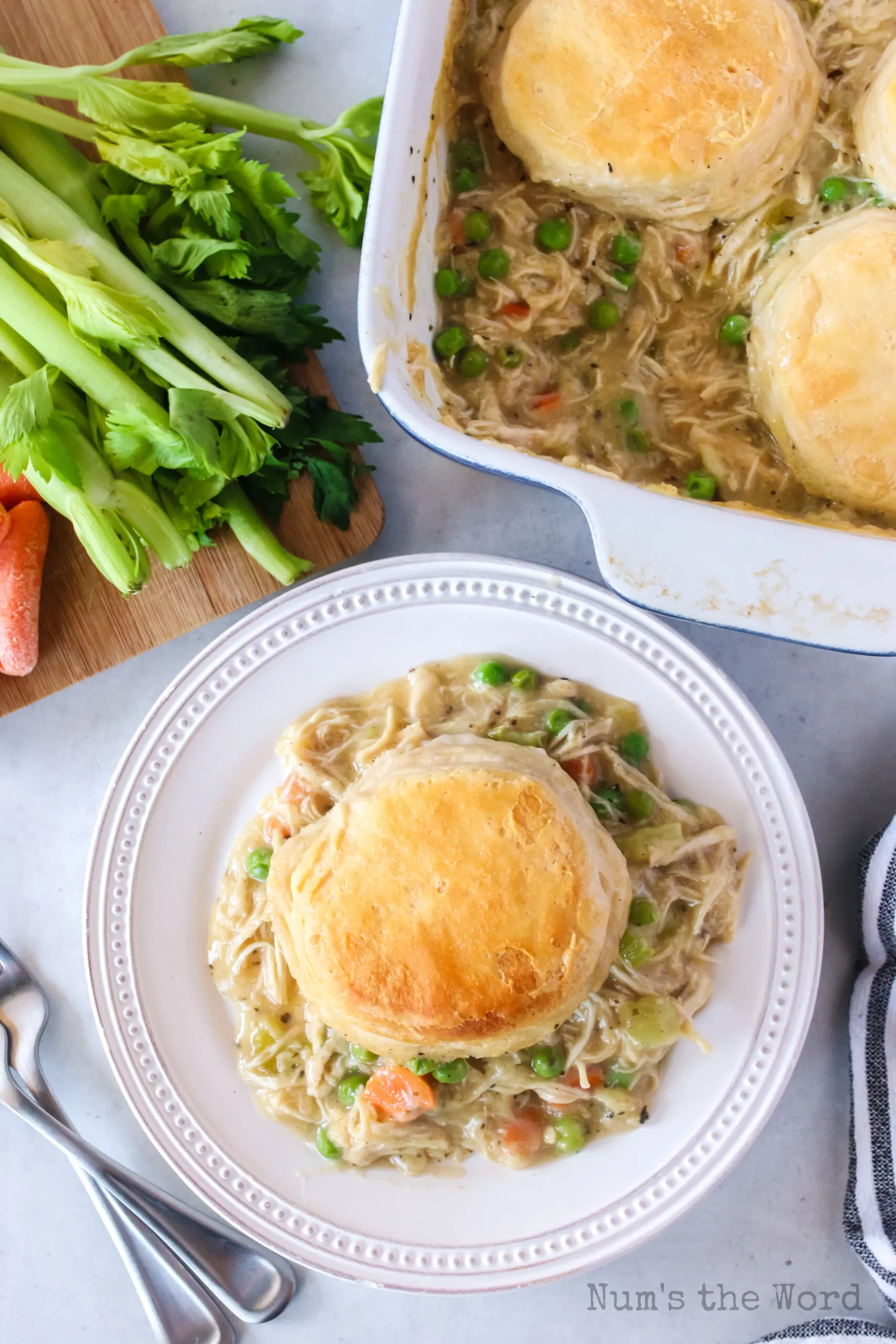 a plate next to casserole with chicken gravy mixture and a biscuit on top