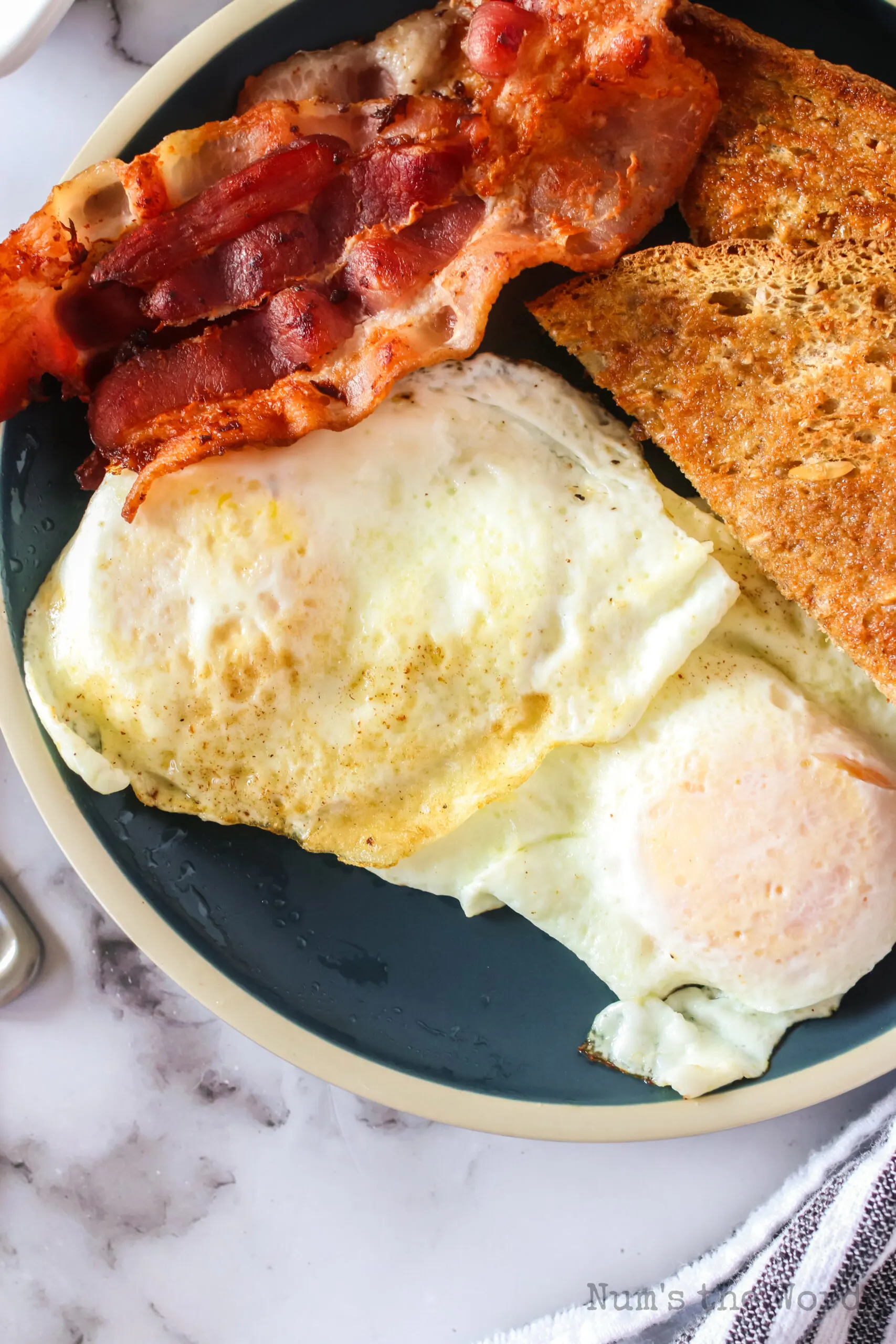 zoomed in top view of eggs on a plate with bacon and toast