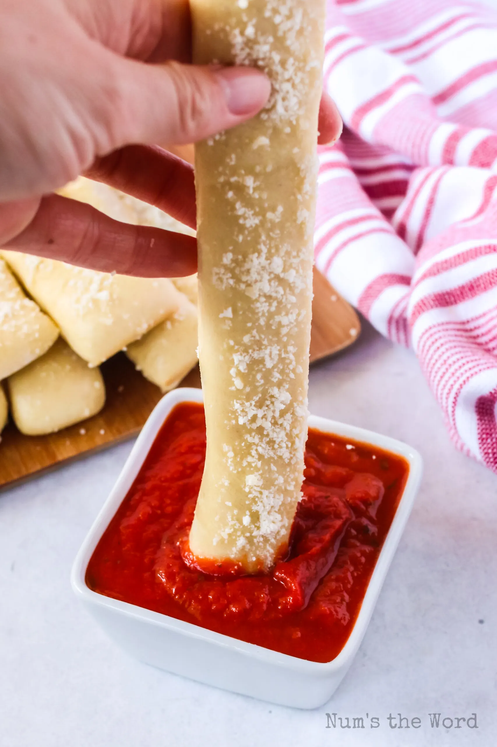 hand dipping a bread stick in marinara sauce