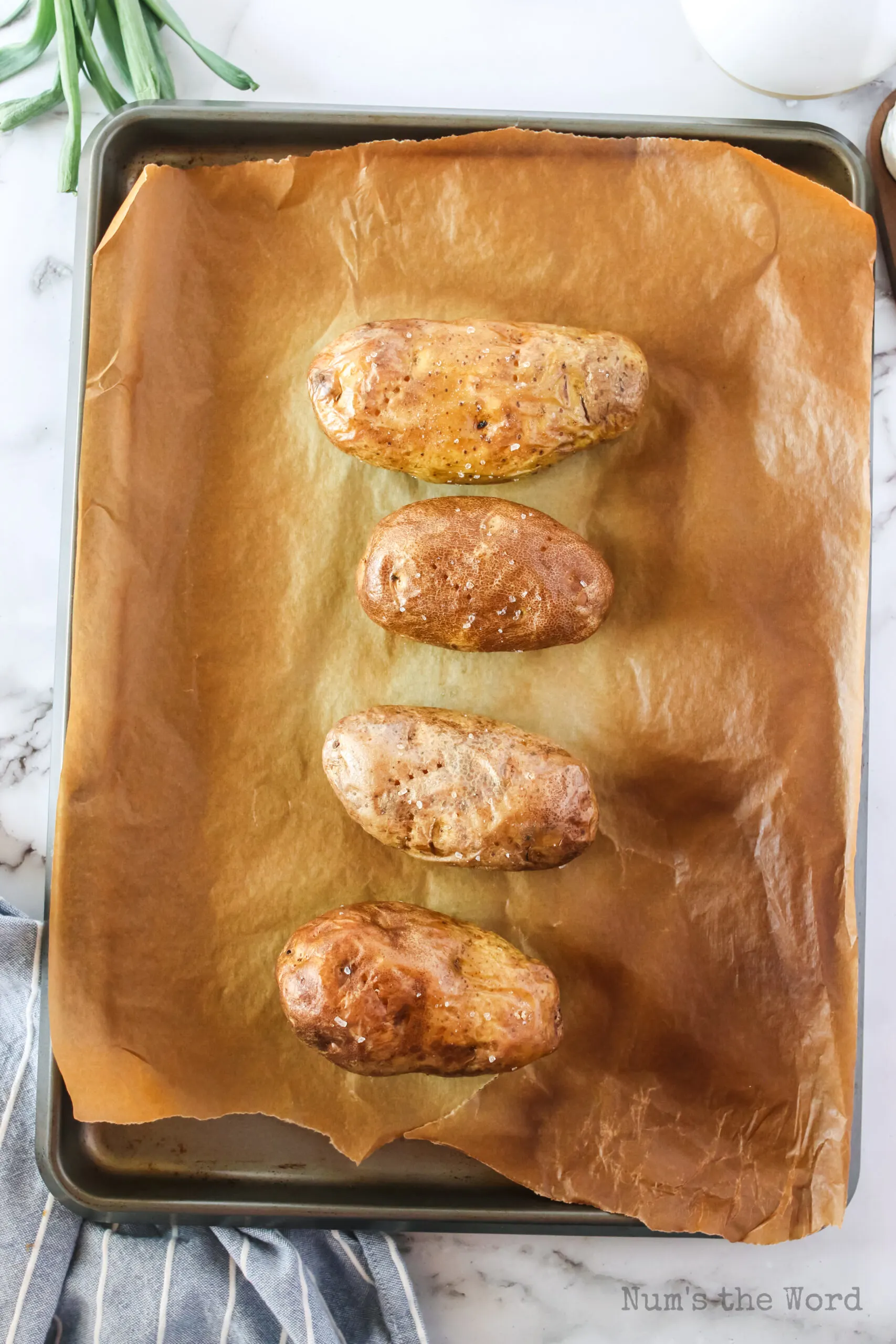 4 potatoes on baking sheet cooked and ready to serve