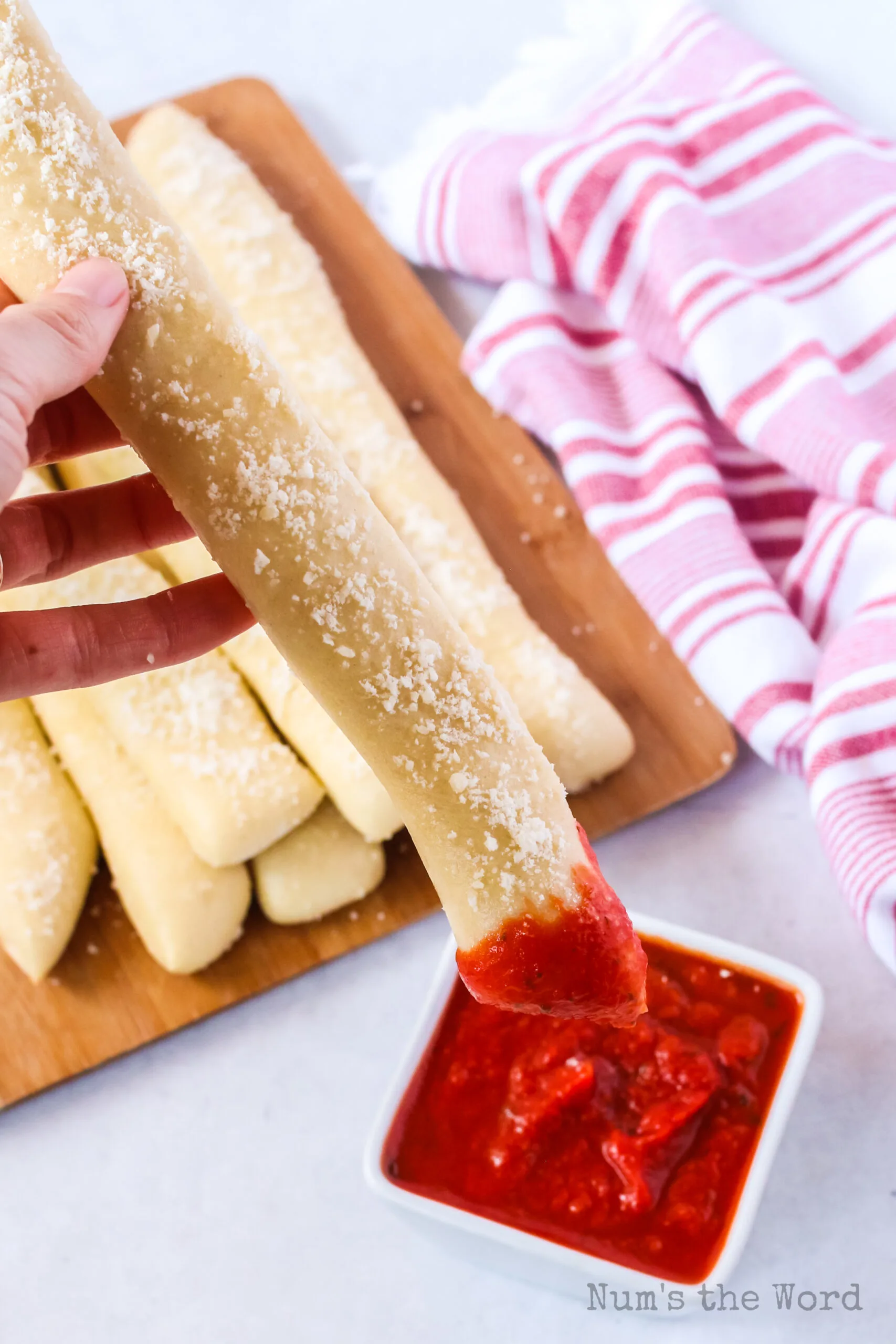 hand holding bread stick with marinara sauce on the end