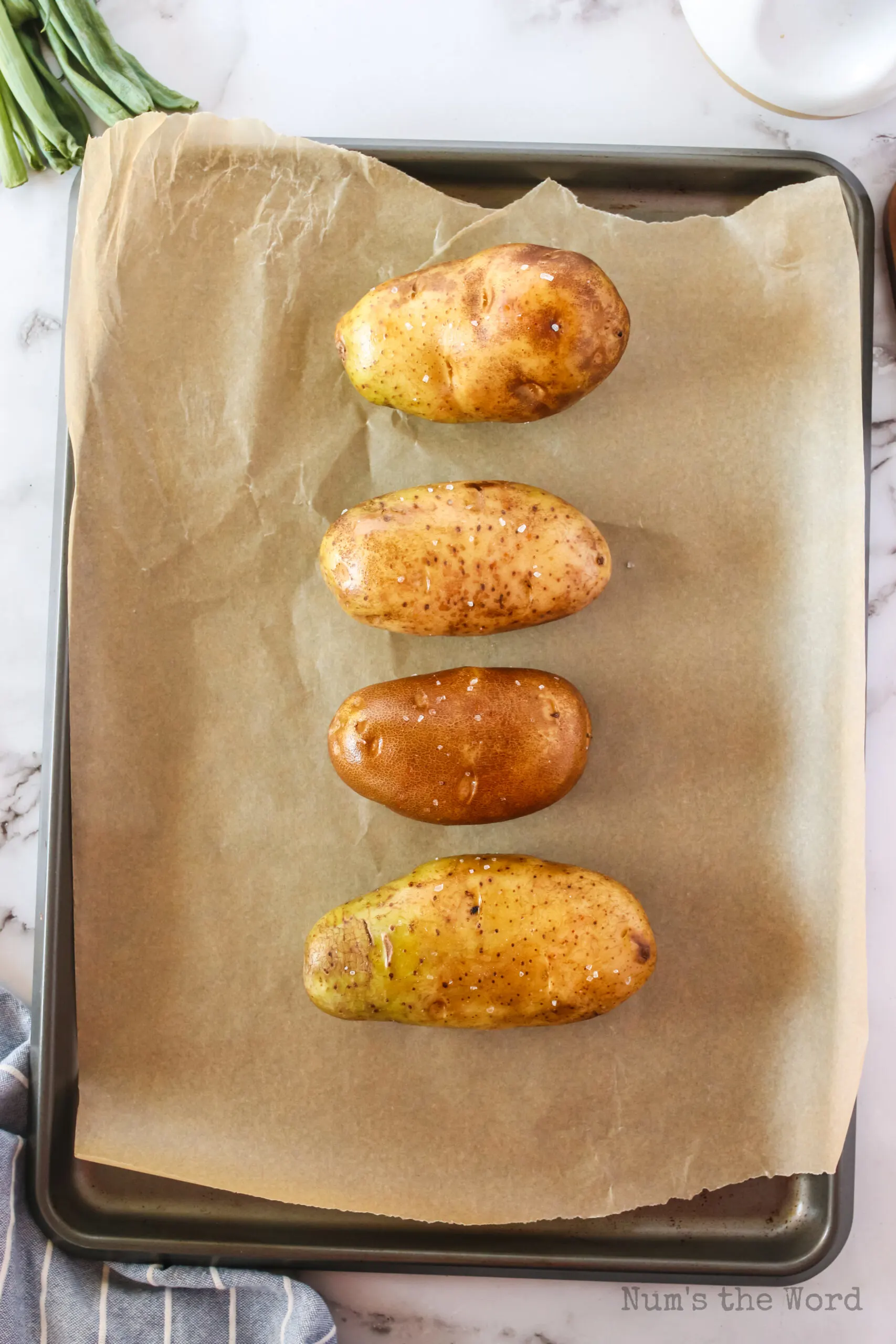 4 potatoes on cooking sheet and ready to be baked