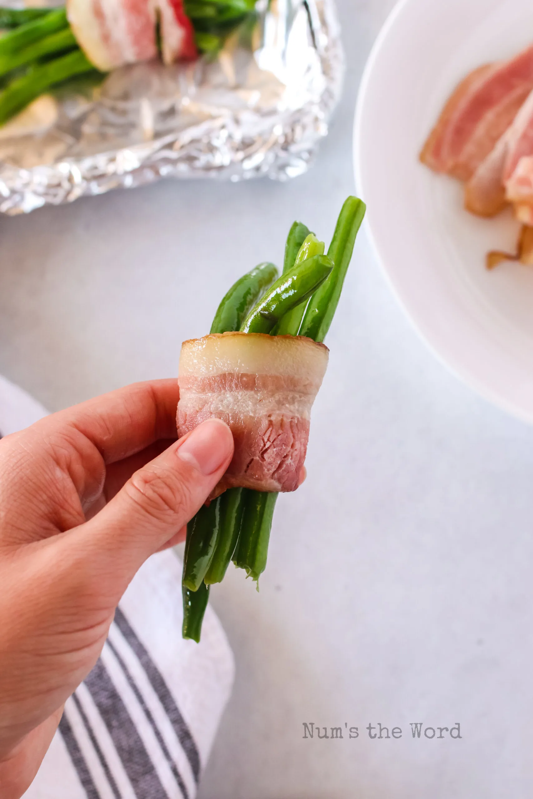 hand holding a bundle to show how to wrap the green beans.