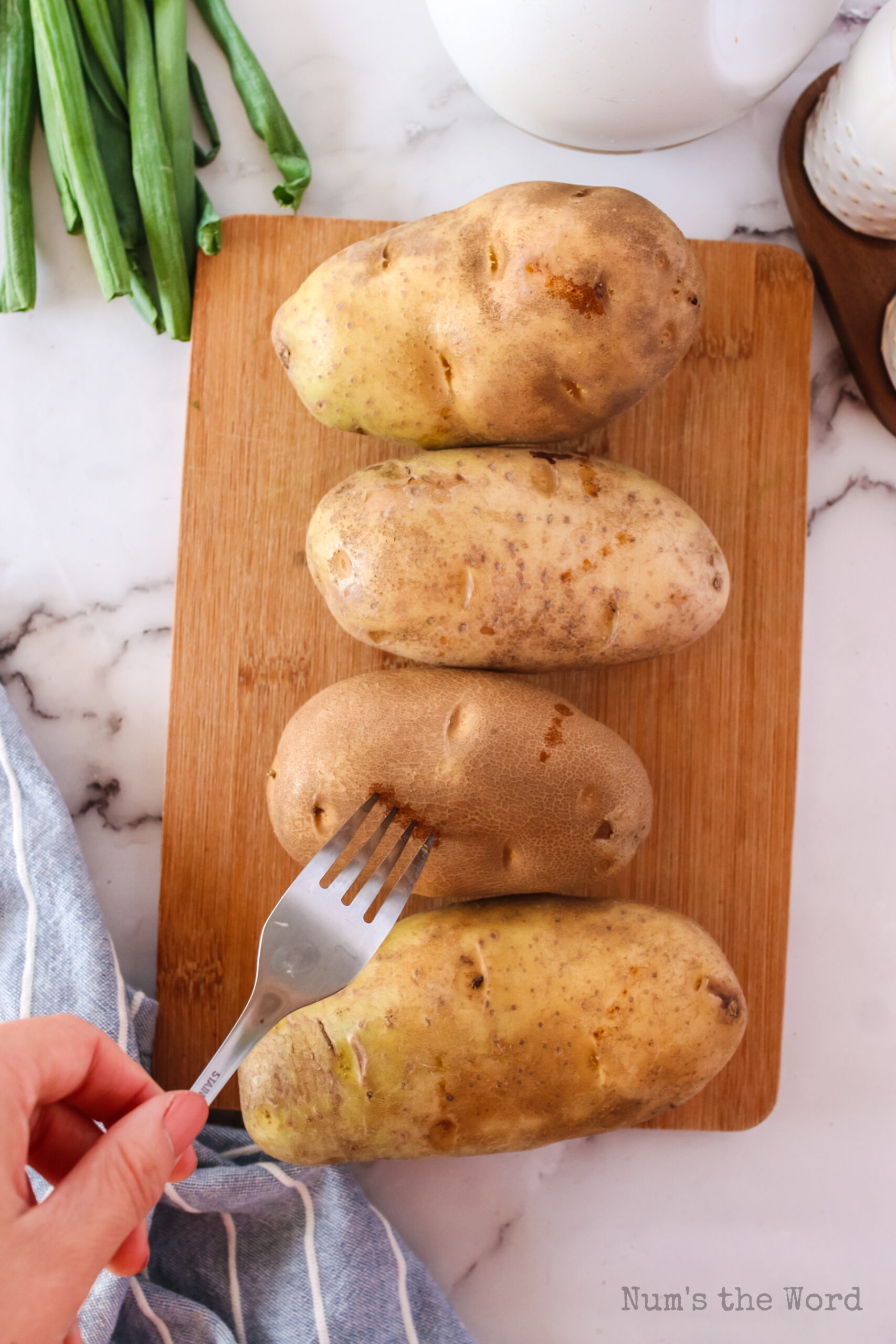 hand with fork pricking potatoes