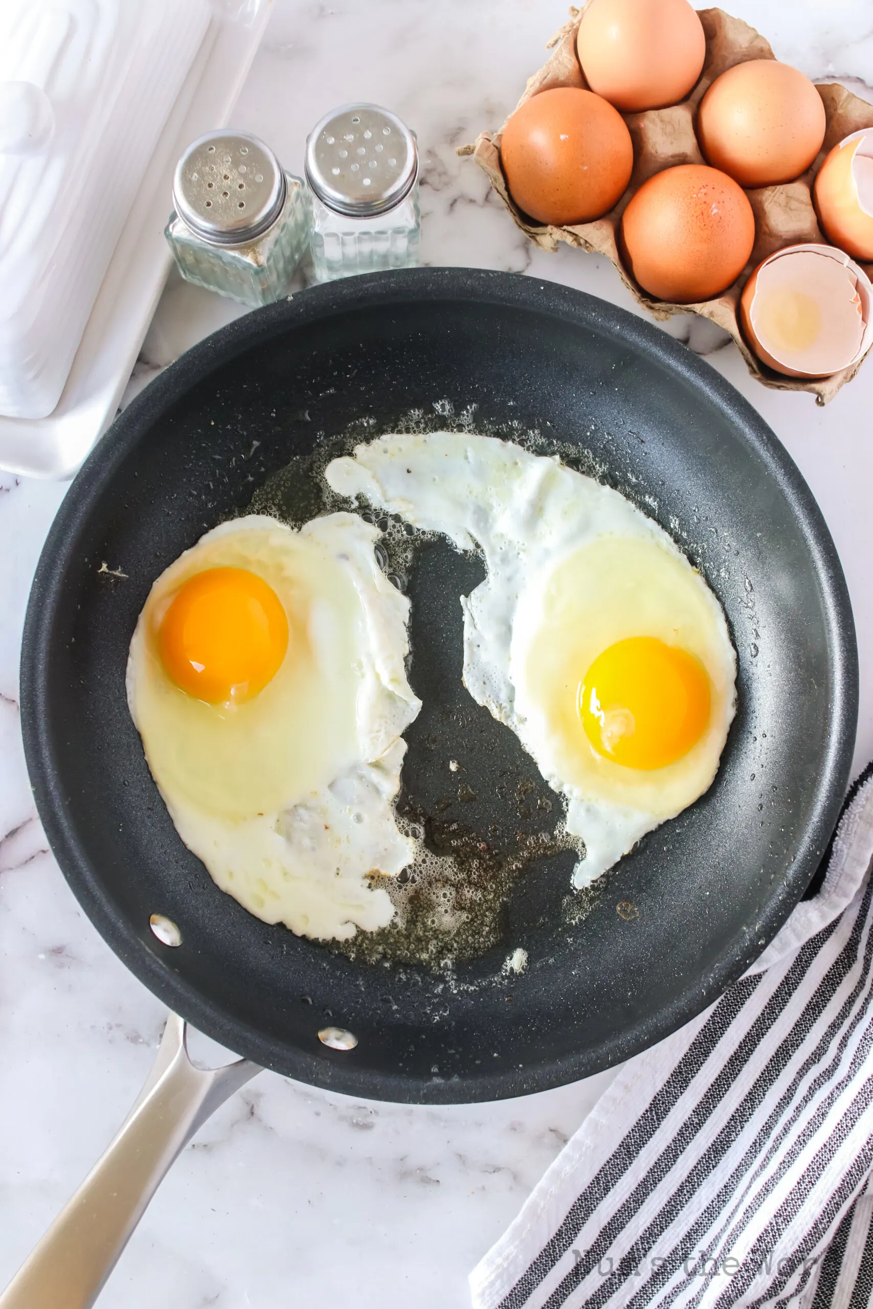 two eggs placed in a greased non stick pan