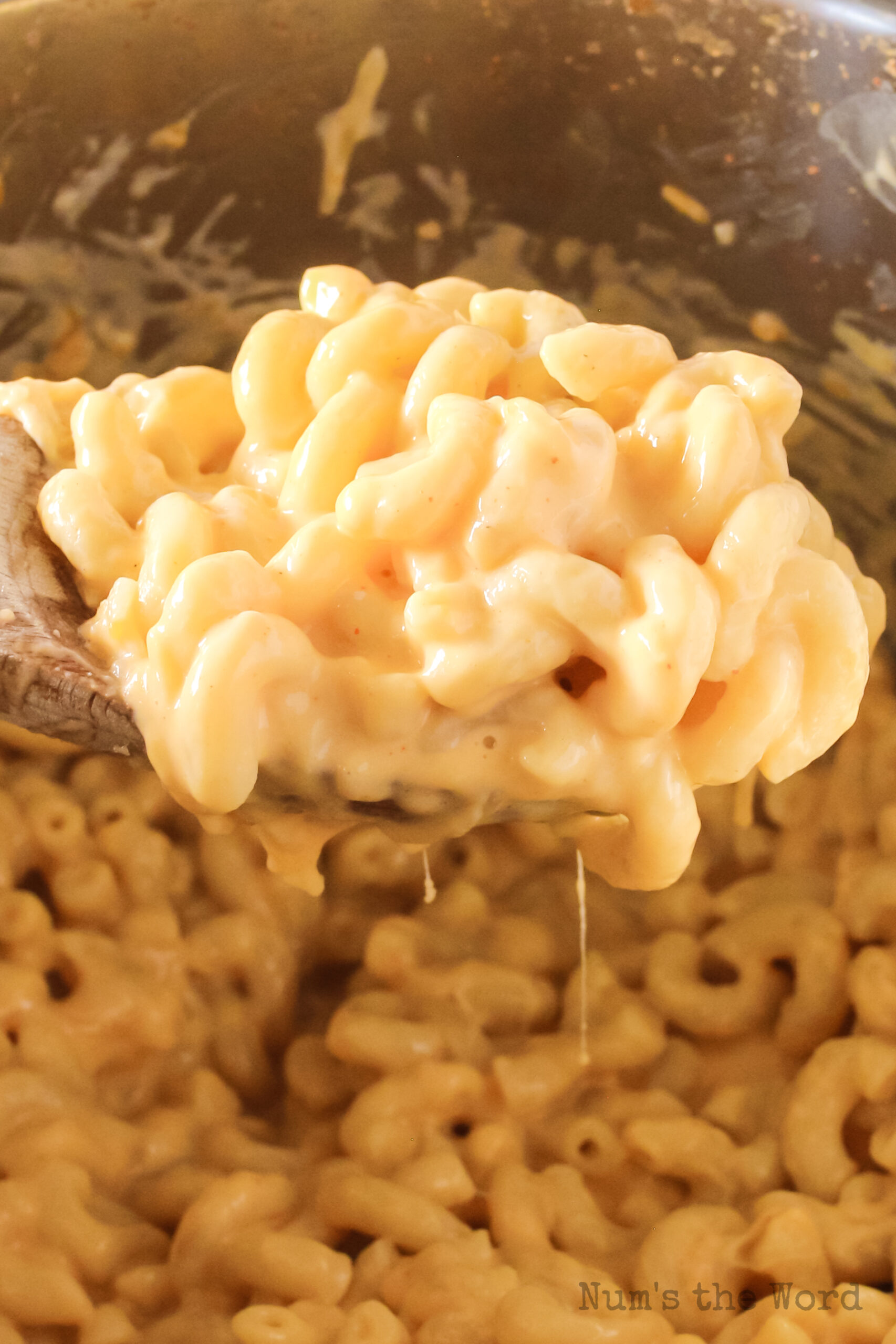 wooden spoon scooping macaroni and cheese from the instant pot