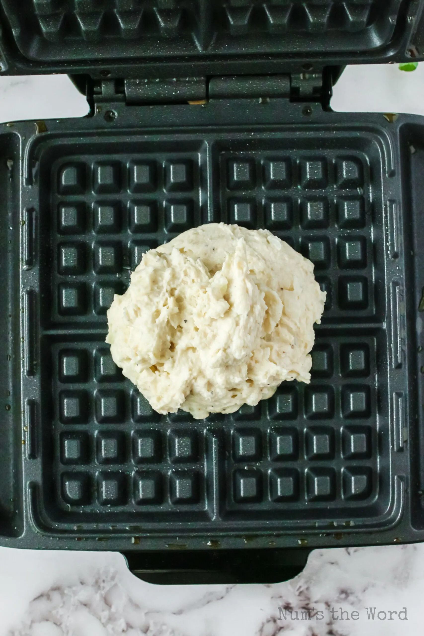 potato waffle batter placed in a waffle iron