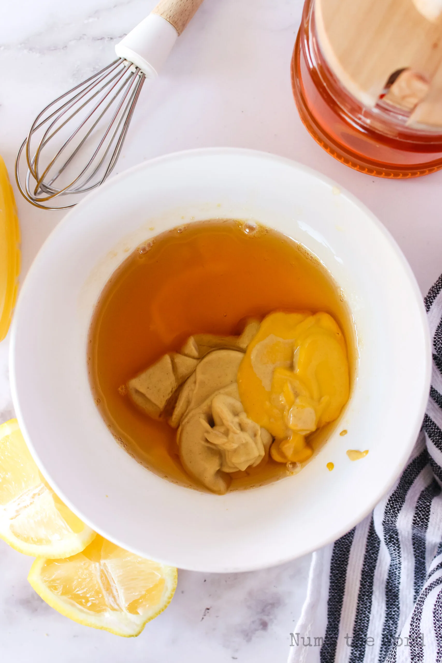 honey, lemon juice, dijon mustard and yellow mustard added to a bowl, unmixed