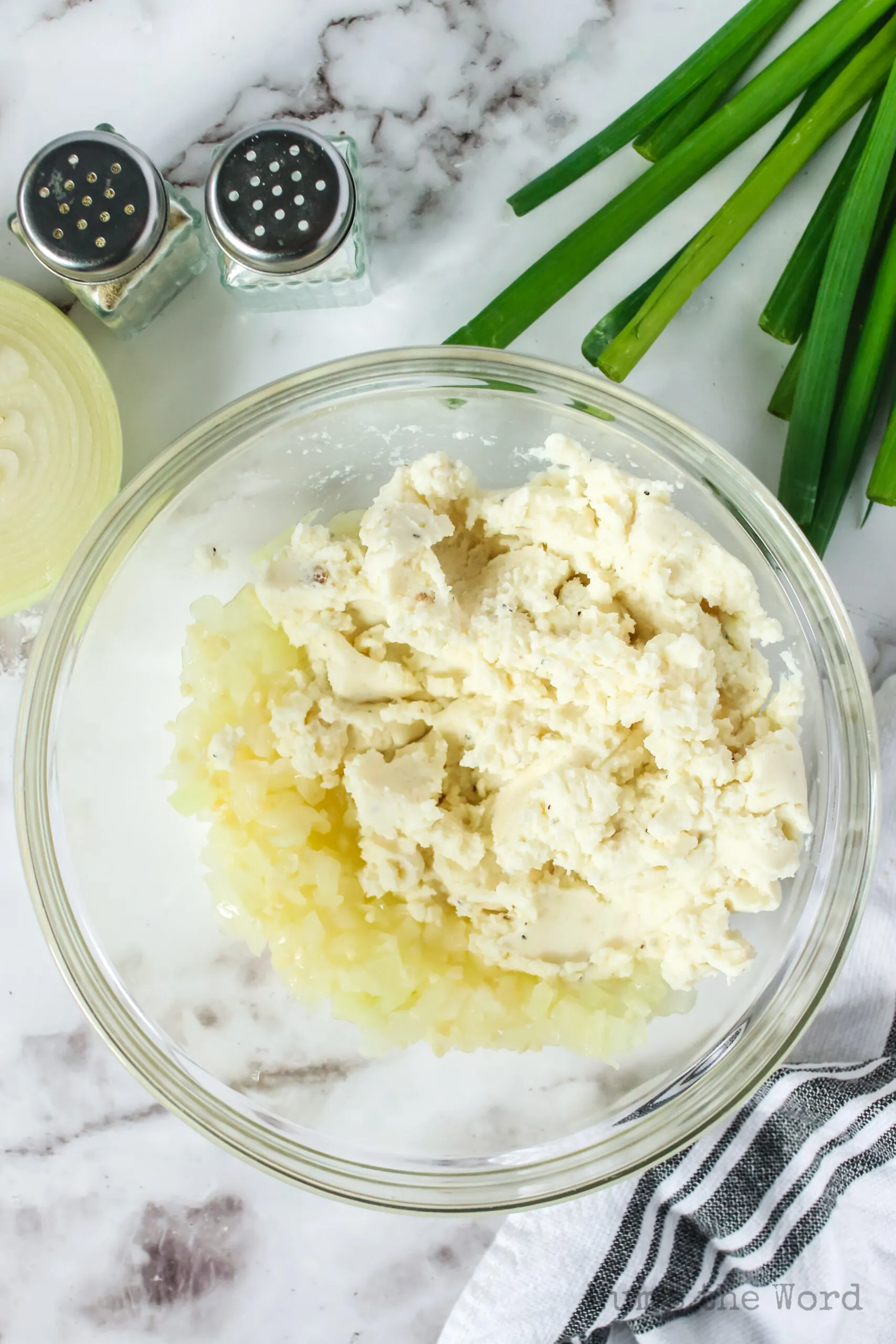 cooked garlic, butter and onion in a bowl with mashed potatoes added